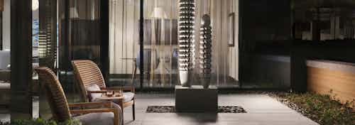 Outdoor seating area at AMLI Fountain Place apartments with two brown chairs and large two pillar stone art sculpture
