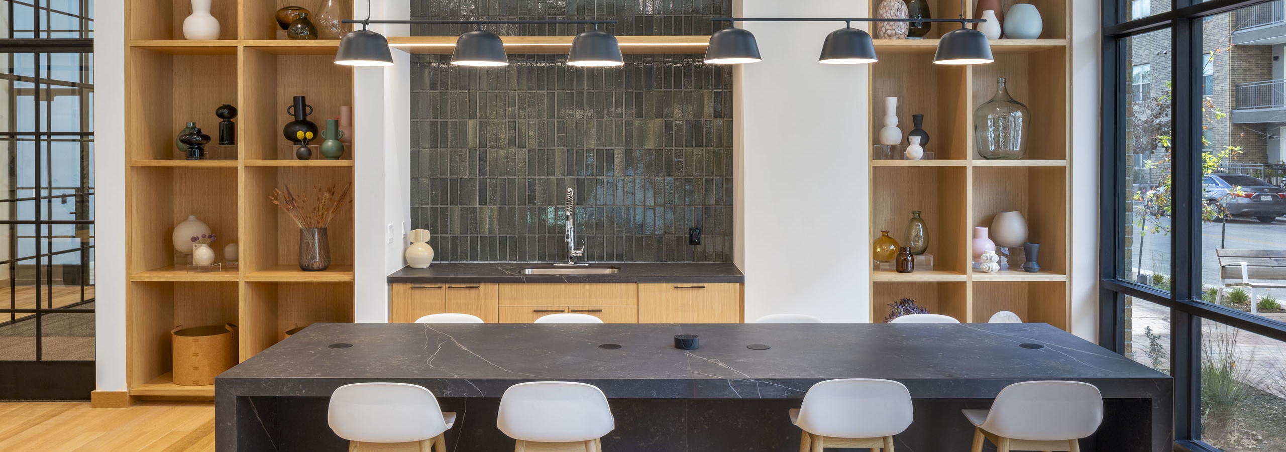 Coworking space at AMLI Branch Park apartments featuring a large quartz kitchen island flanked by two large wooden shelves