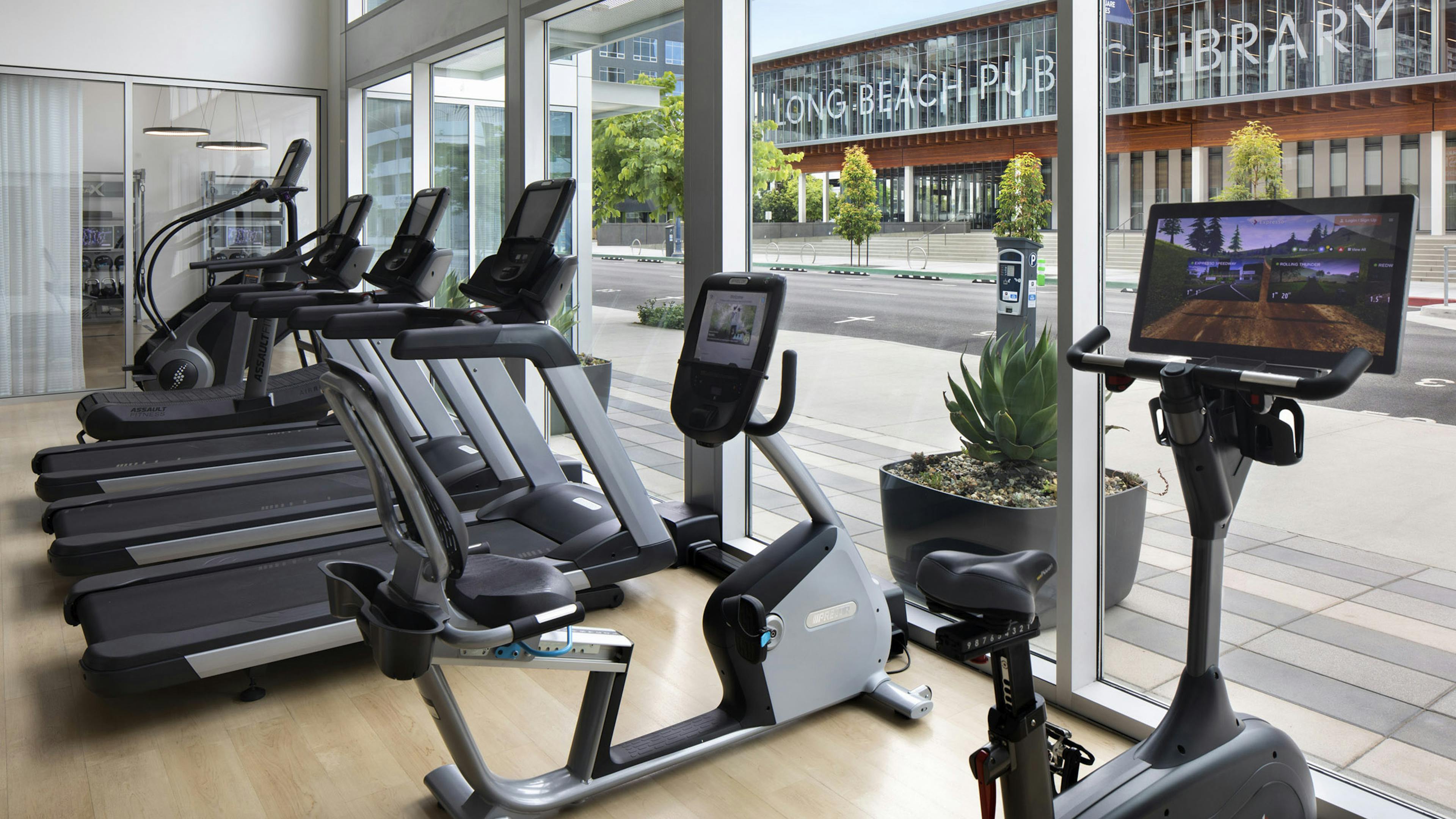 AMLI Park Broadway apartment fitness center with cardio equipment facing large windows with view of the city street