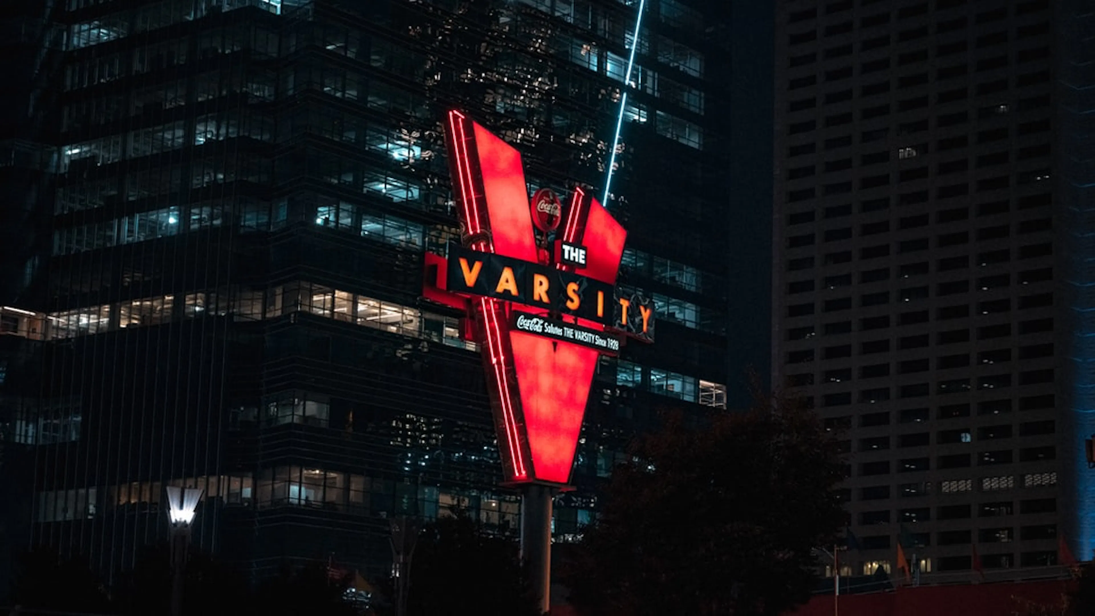 The large neon sign for The Varsity restaurant against a backdrop of skyscrapers