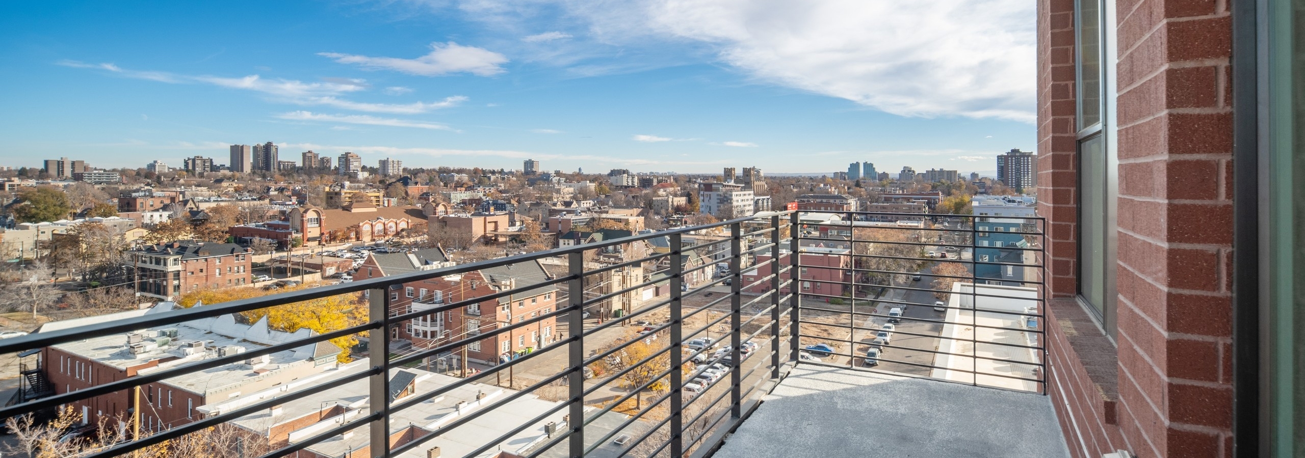 AMLI at Uptown apartment balcony with modern metal railing looking down onto vibrant city buildings in the daytime