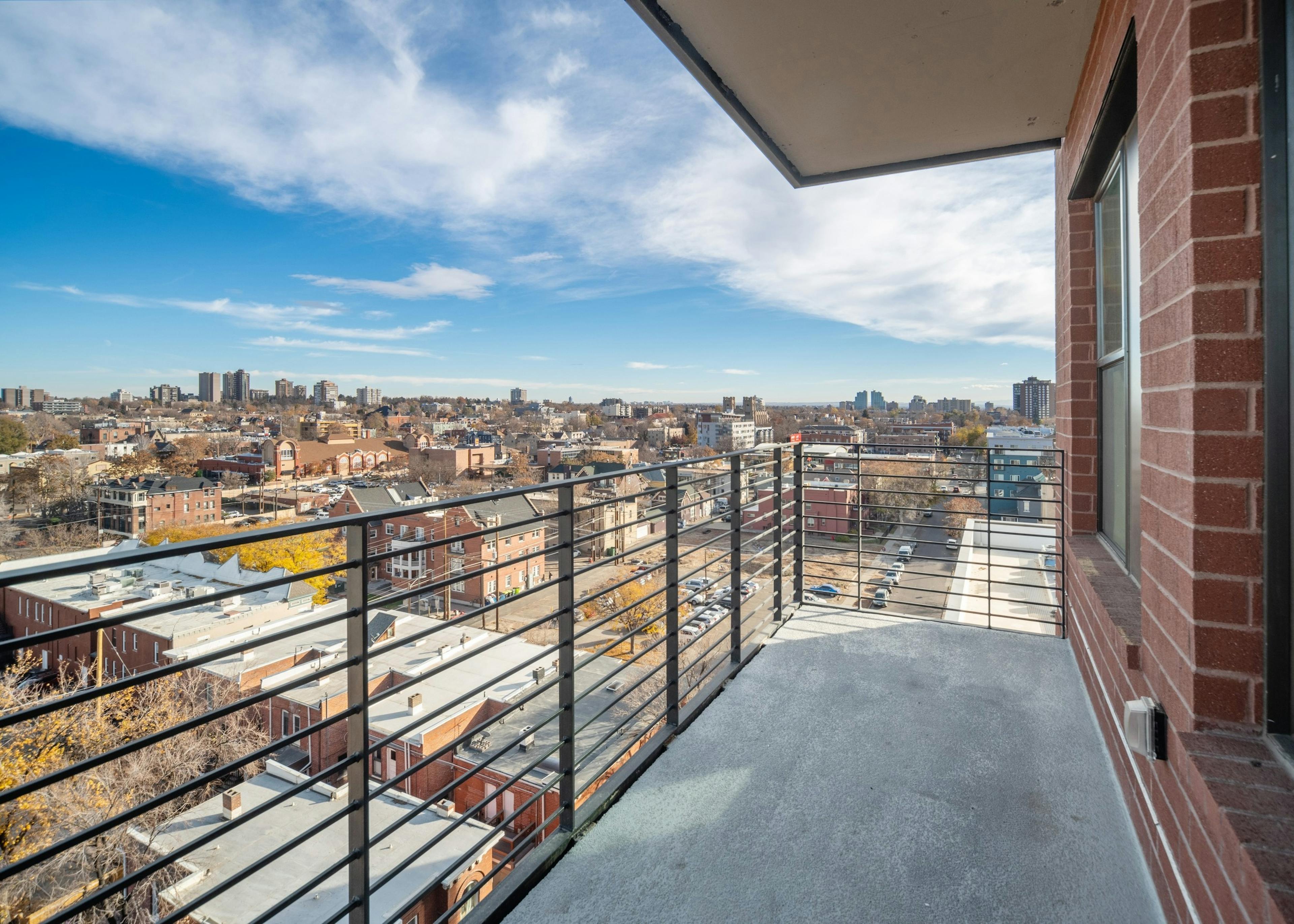AMLI at Uptown apartment balcony with modern metal railing looking down onto vibrant city buildings in the daytime