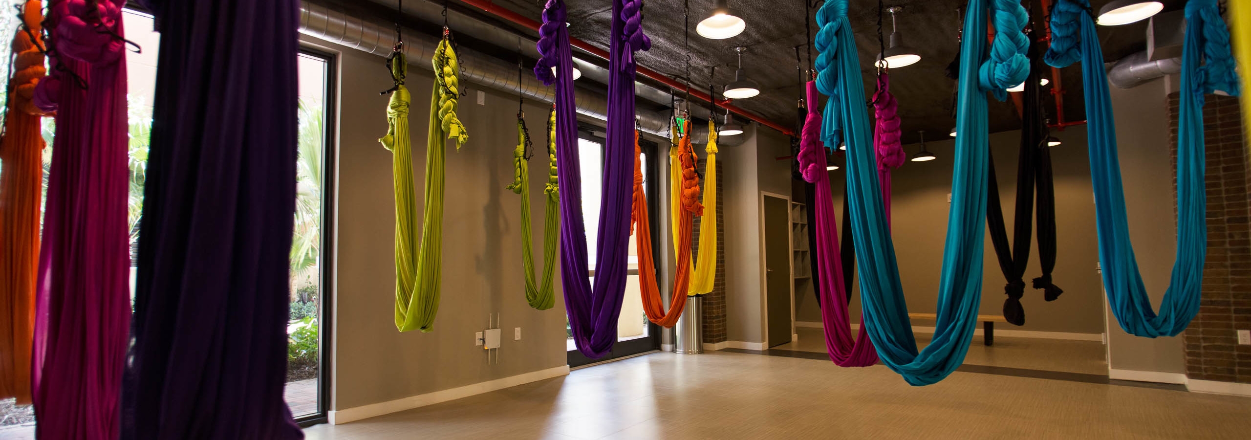 The aerial yoga studio at AMLI Dadeland with multiple vibrant colored hammocks hanging from the ceiling