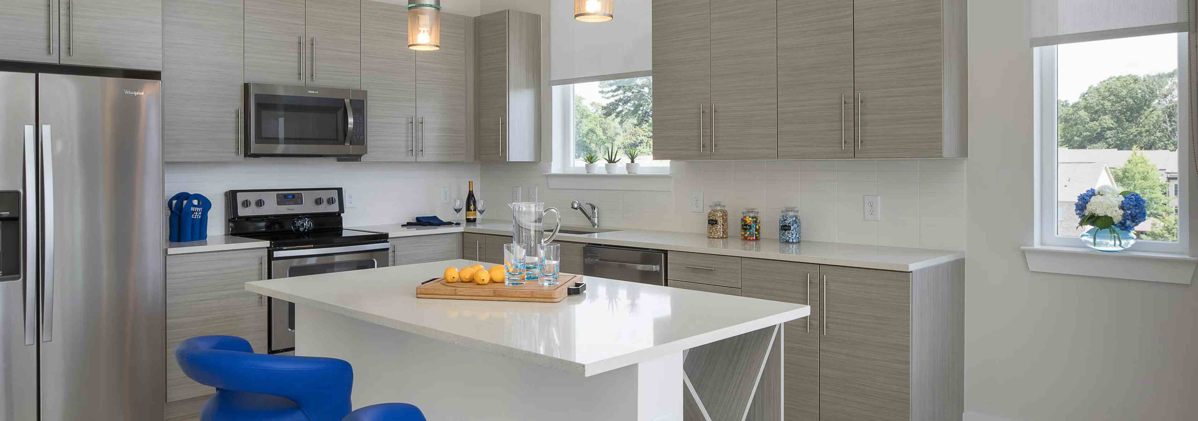 Interior of AMLI Buckhead kitchen with grey cabinets and sleek white countertops with stainless steel appliances and island