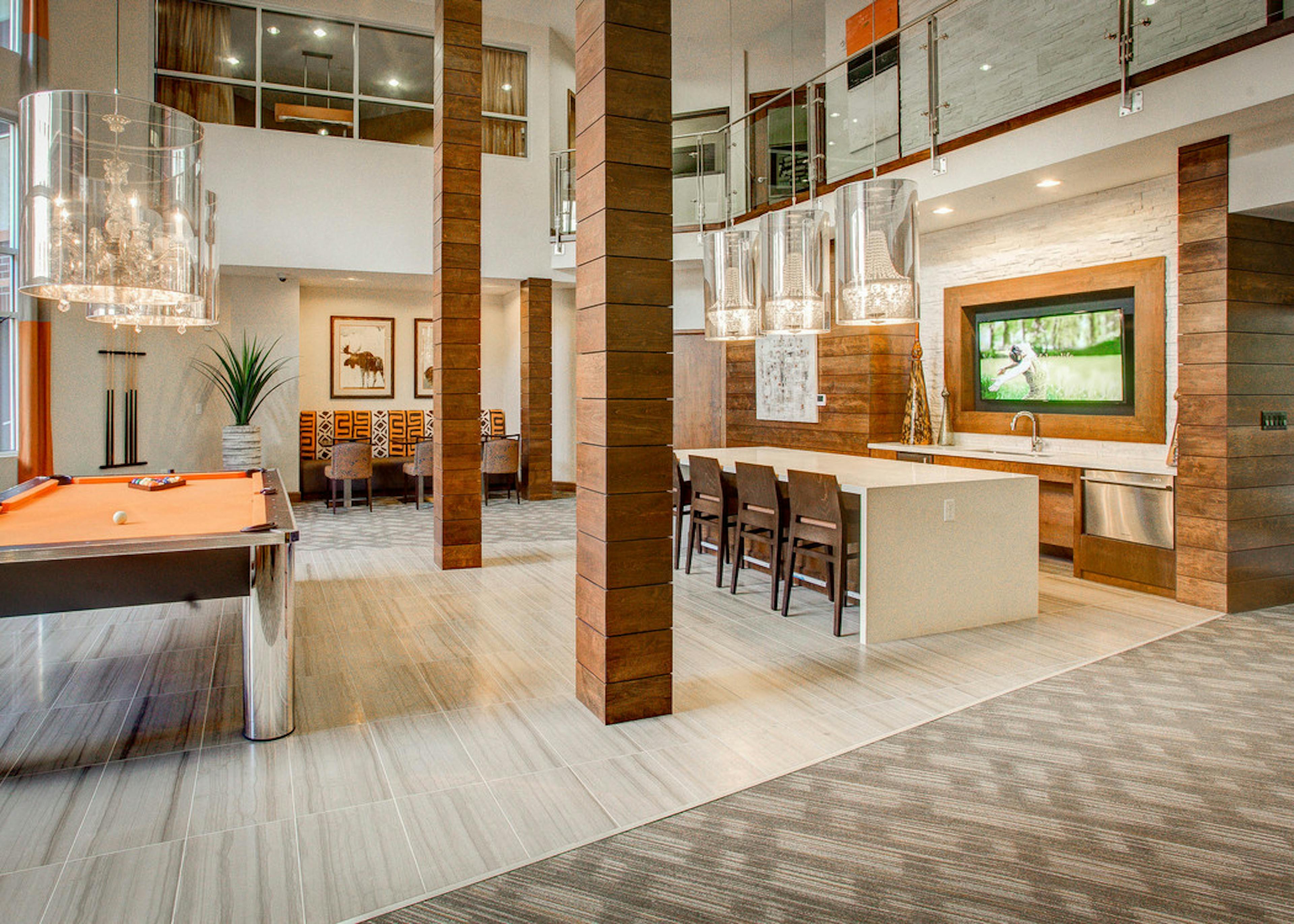 Interior view of the club room at AMLI Riverfront Park apartments with a pool table and television and a table with chairs