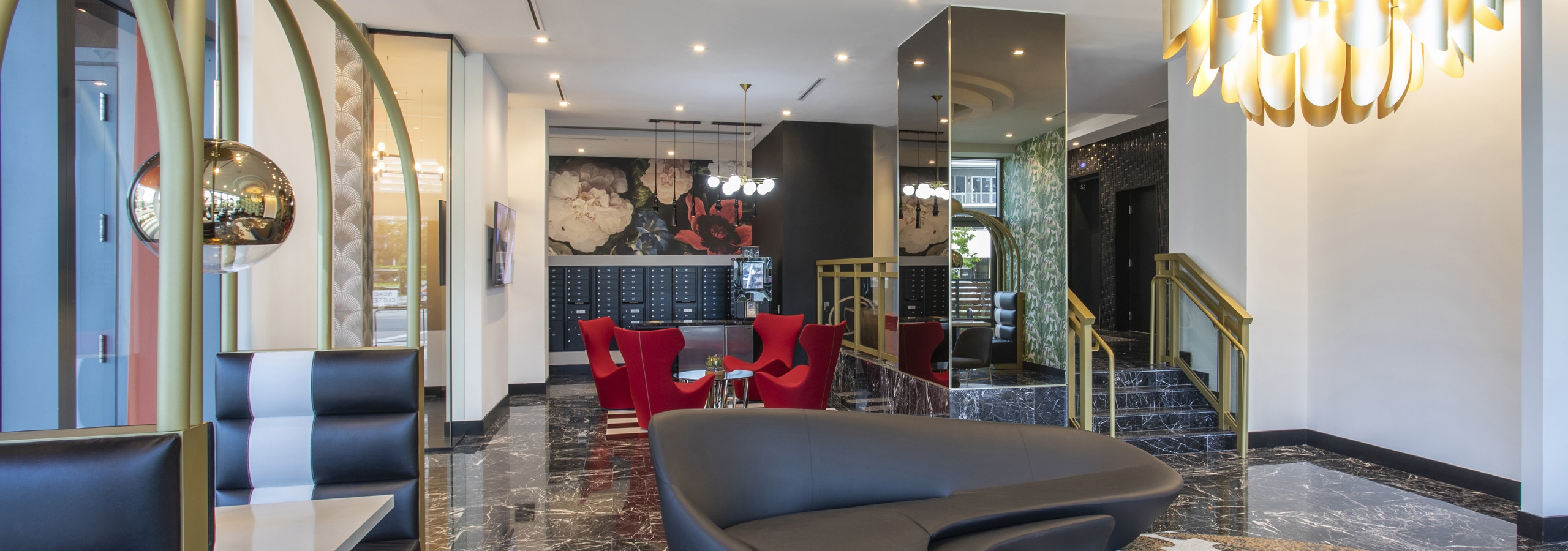 AMLI Midtown Miami with modern black sofa and gold chandelier and mirrored pillar and mail boxes with red chairs at back