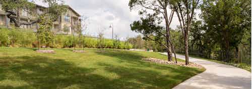 AMLI Covered Bridge’s paved hiking and biking trail that is enclosed by lush green grass and mature trees