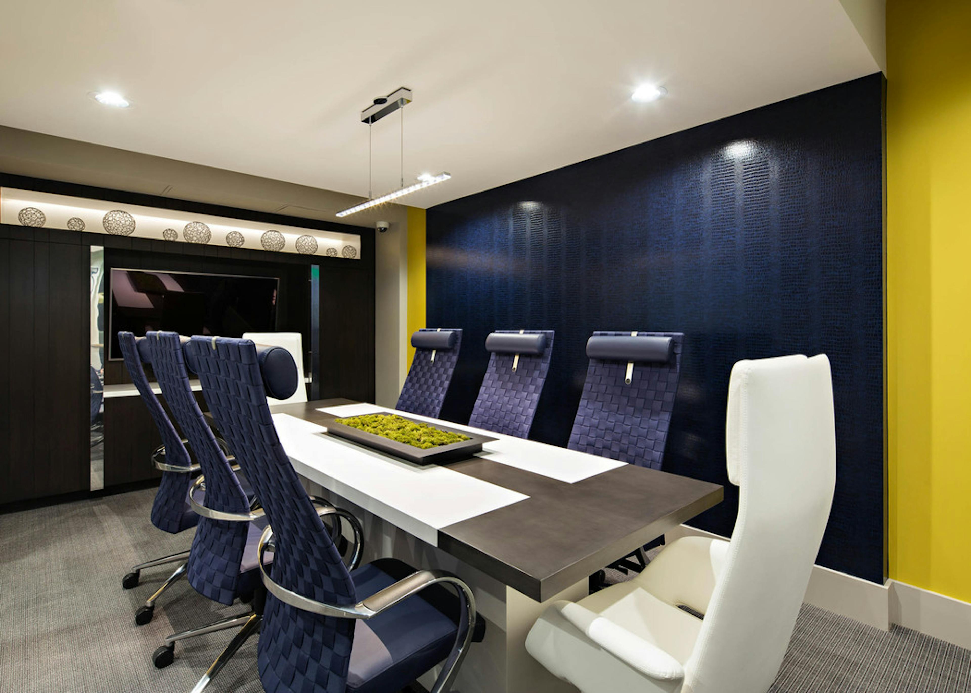 Interior view of the business center conference table at AMLI Lex on Orange apartments with big blue chairs and big screen TV