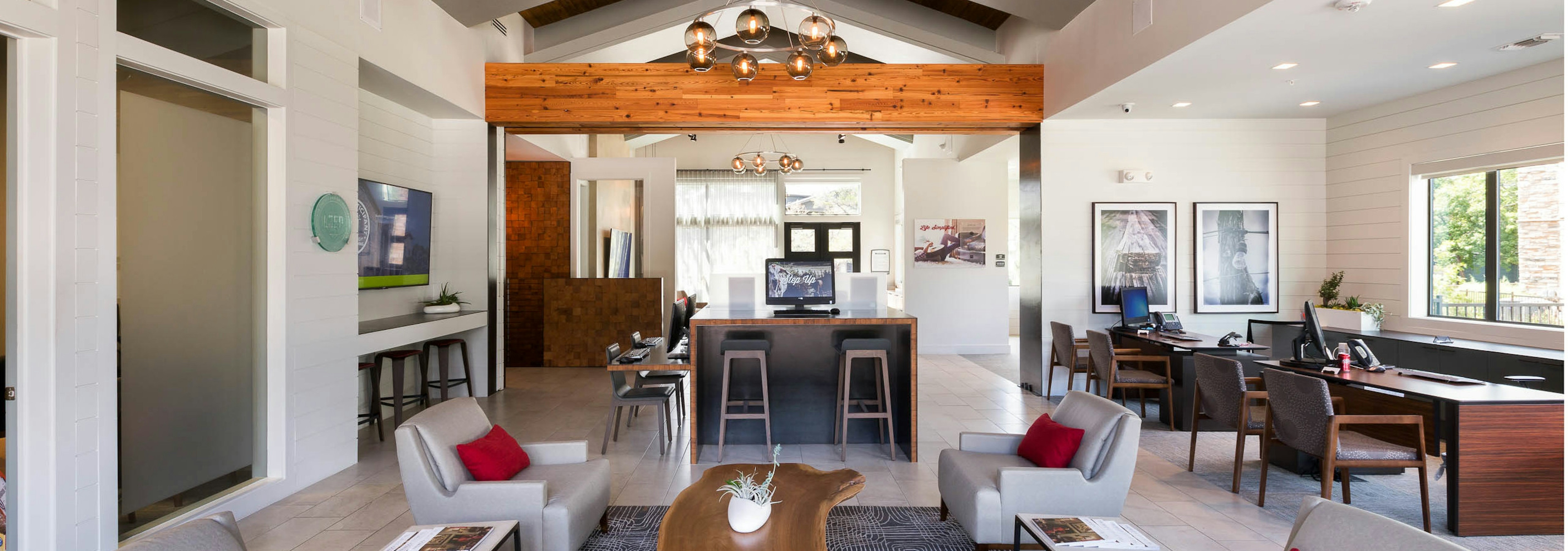 AMLI Covered Bridge leasing office with light tile flooring, lounge chairs with pillows, and a wooden accent beam