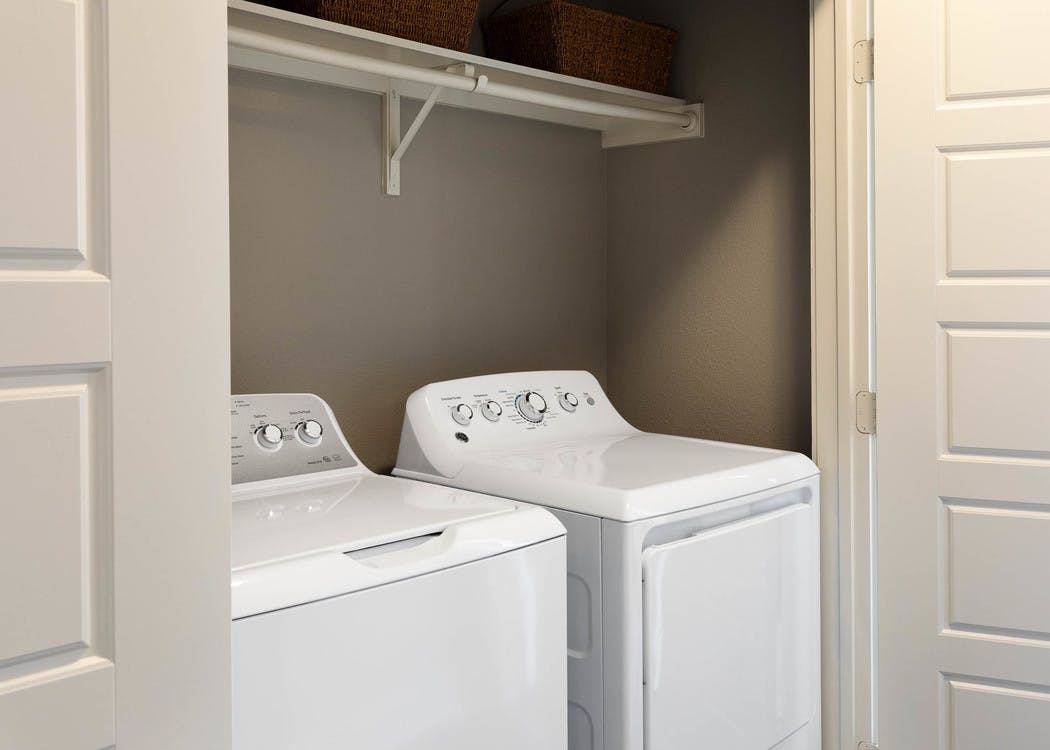 Interior view of full size white GE washer and dryer tucked away in closet at AMLI South Shore apartment community