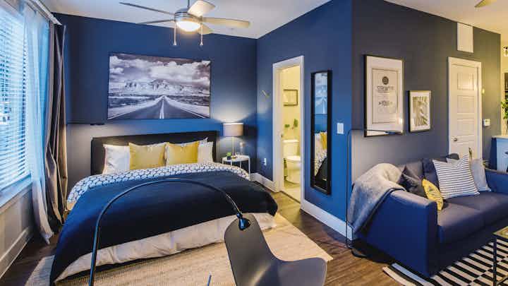 Interior view of AMLI at the Ballpark furnished studio apartment with bedroom and living room areas with blue walls