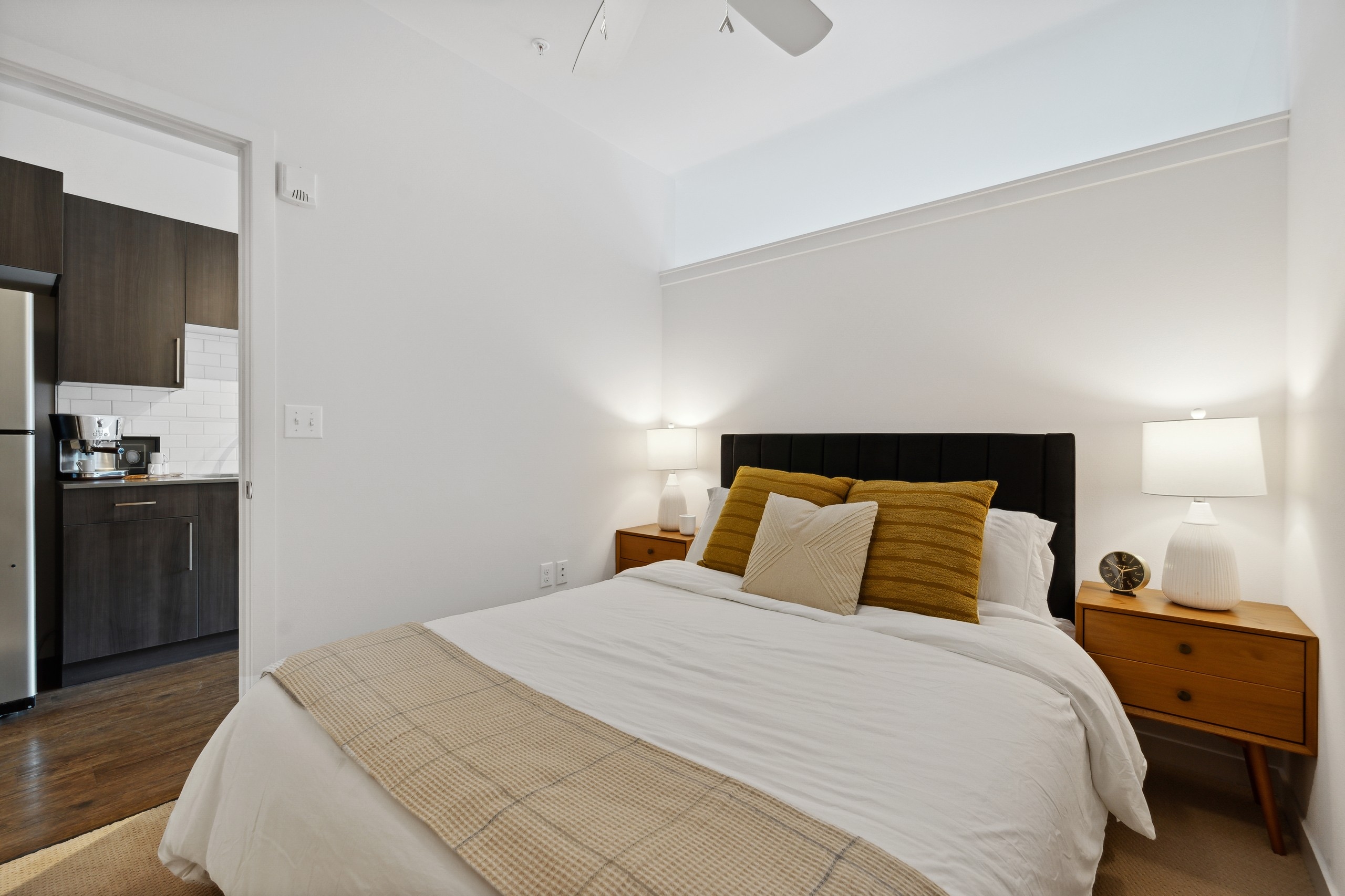 Interior view of a bedroom at AMLI South Lake Union with a bed and wooden side tables with lamps and a view into the kitchen