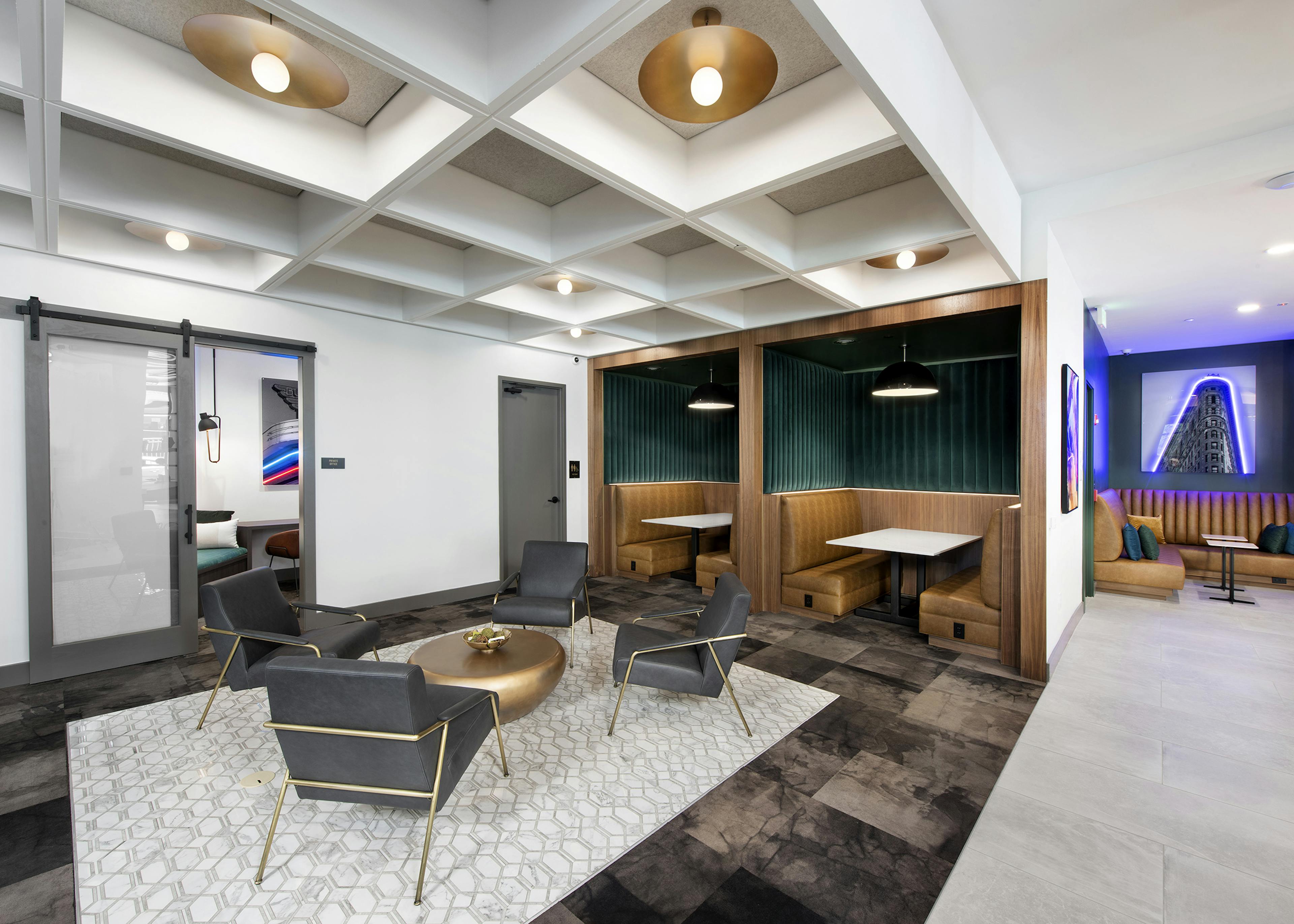 AMLI Flatiron clubhouse with coffered ceiling grey chairs and gold table with banquet seating and neon artwork