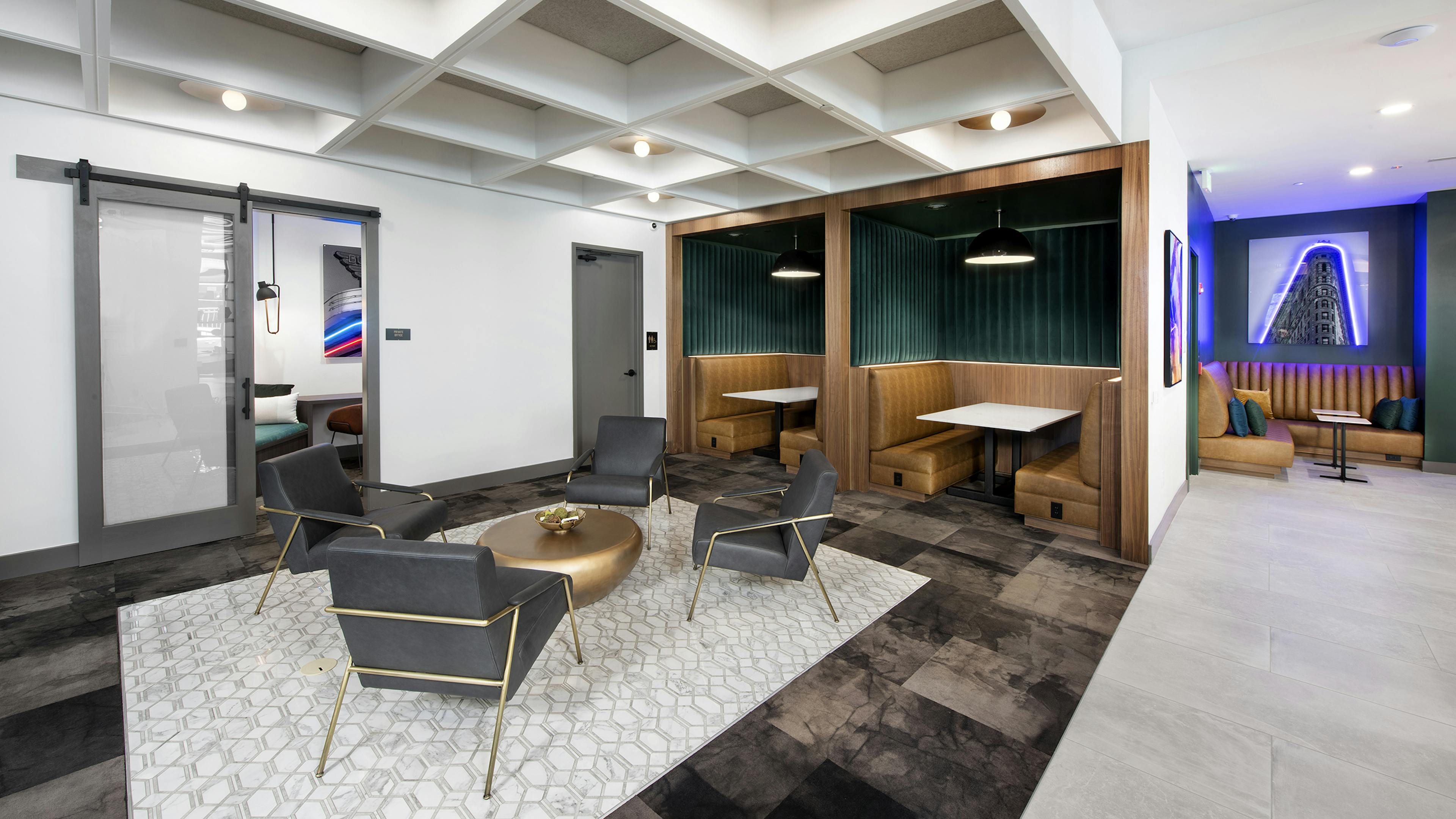AMLI Flatiron clubhouse with coffered ceiling grey chairs and gold table with banquet seating and neon artwork