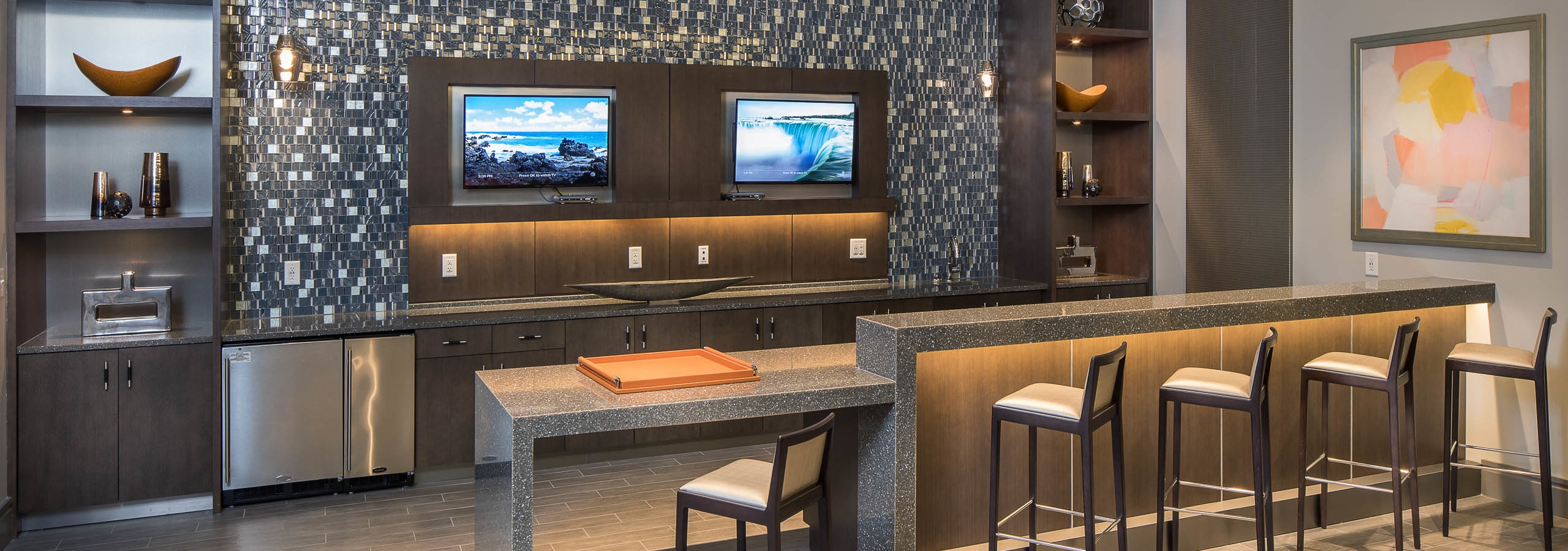 Interior of theatre at AMLI 3464 kitchen area with barstool seating and ample counter space with a patterned backsplash