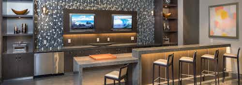 Interior of theatre at AMLI 3464 kitchen area with barstool seating and ample counter space with a patterned backsplash