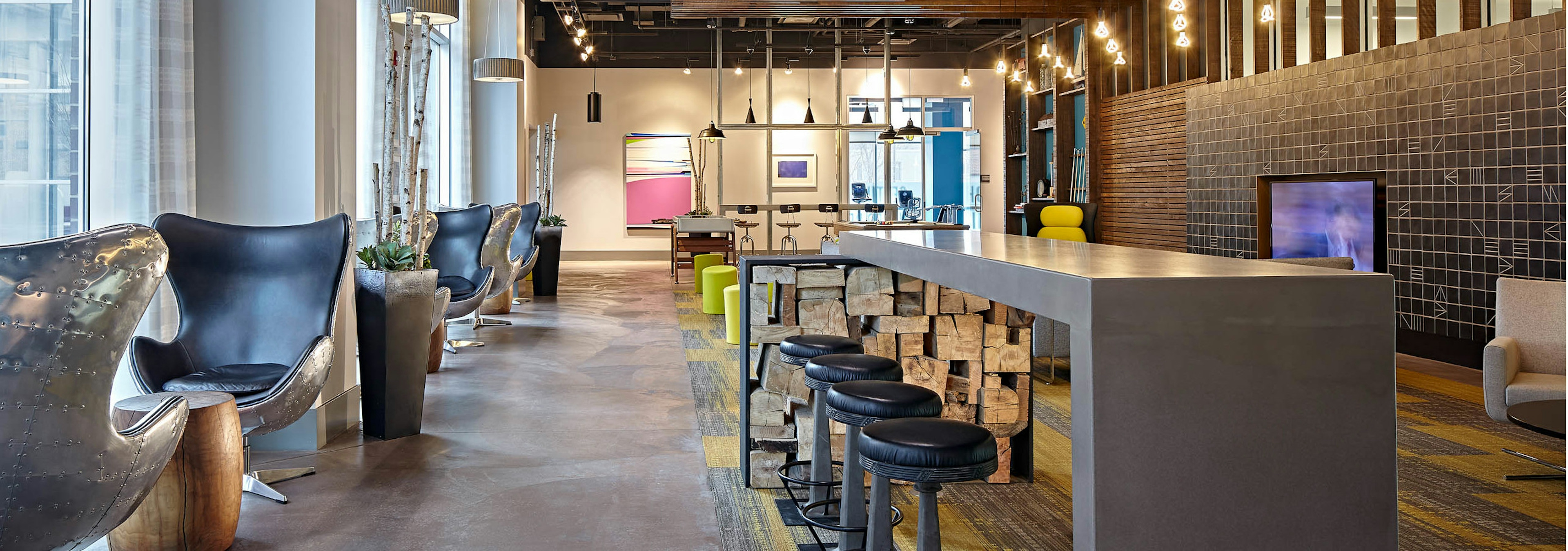 Lounge at AMLI Lofts which has bar stools and swivel chairs positioned by glass windows with hanging textured light fixtures