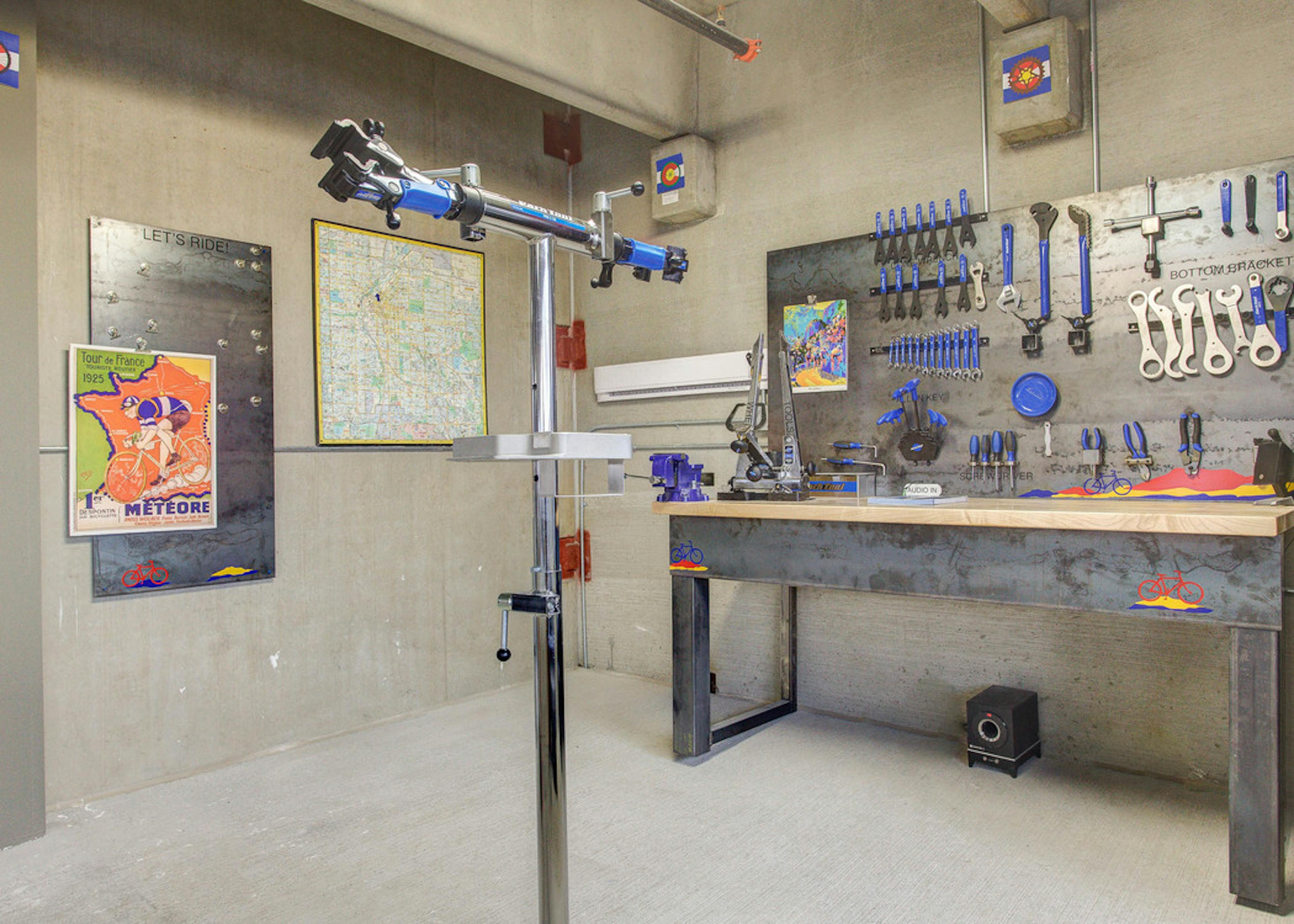 Interior of the bike repair room at AMLI Riverfront Park apartments with a work bench and tools and steel bike repair stand 
