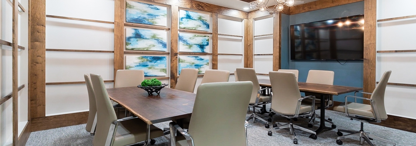 AMLI Old 4th Ward conference room with large TV and two large wood tables and six beige leather chairs at each
