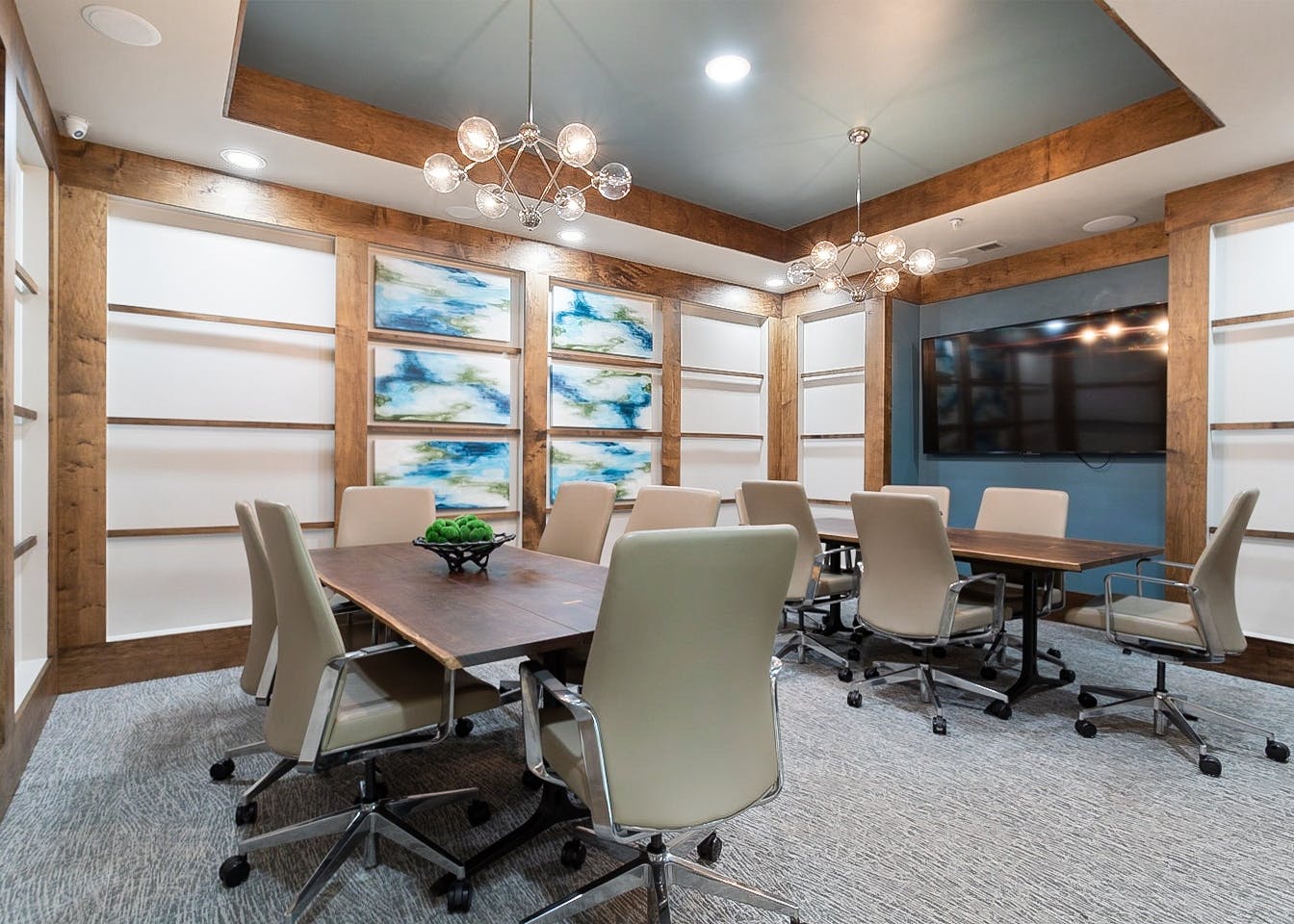 AMLI Old 4th Ward conference room with large TV and two large wood tables and six beige leather chairs at each
