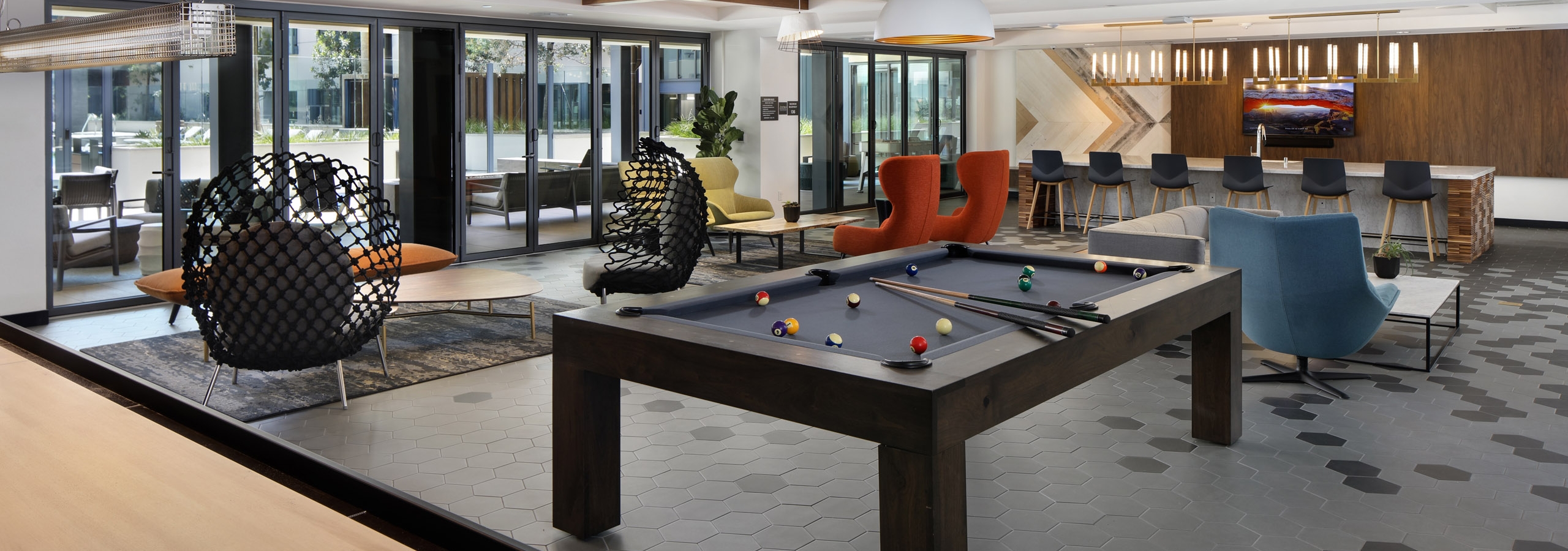 AMLI Old Pasadena clubroom with shuffleboard and billiard table and various colorful lounge seating and view to pool