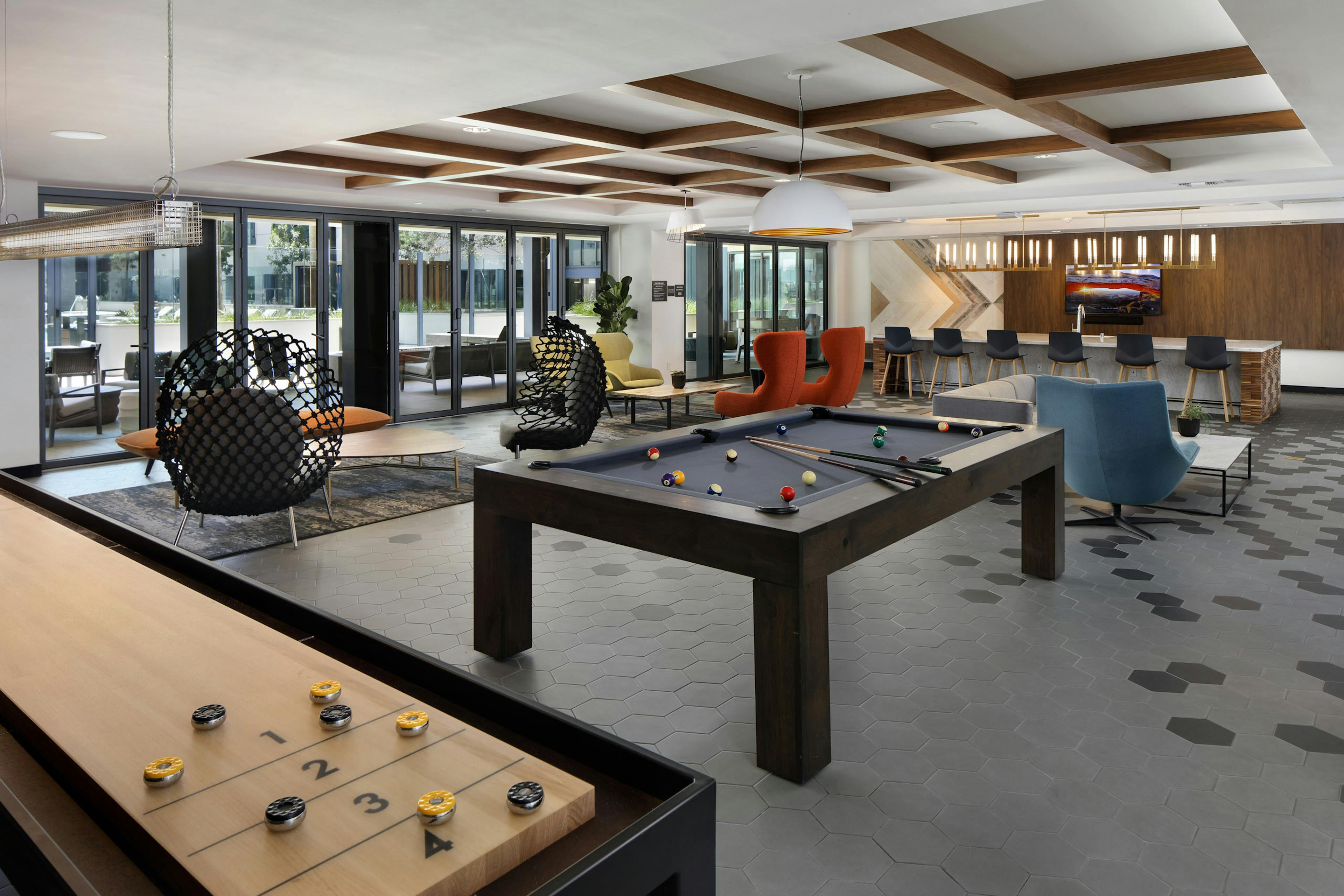 AMLI Old Pasadena clubroom with shuffleboard and billiard table and various colorful lounge seating and view to pool 