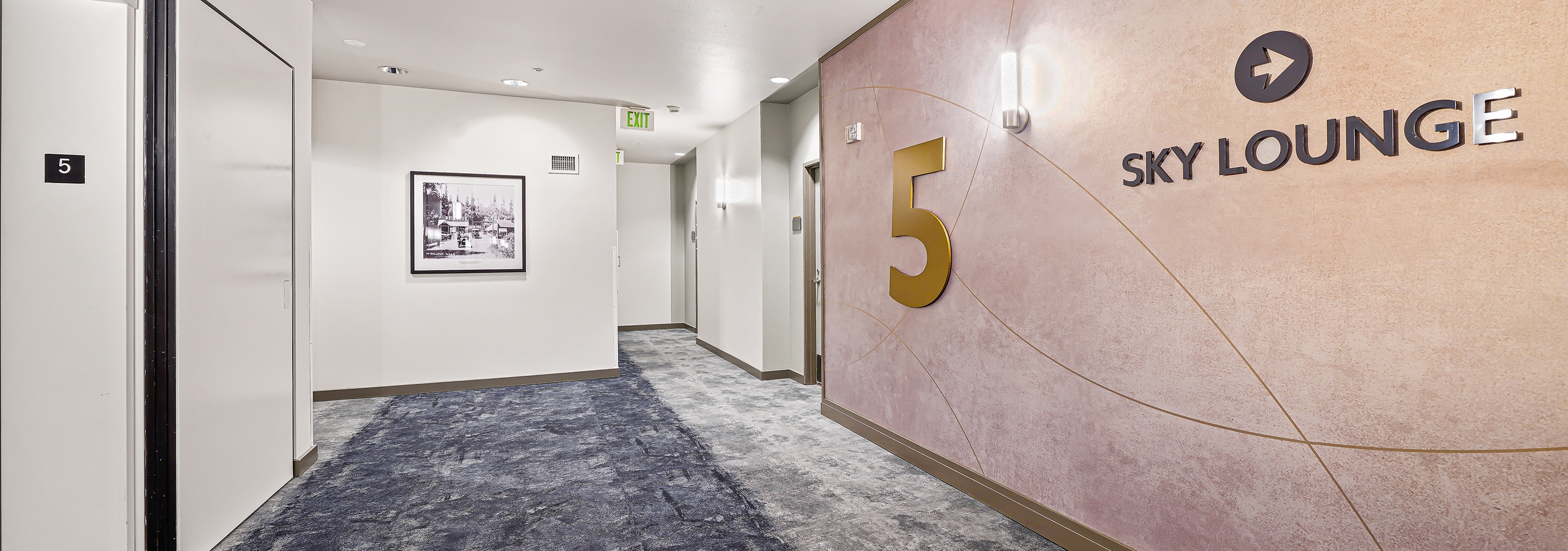 Sky lounge and 5 on tan wall in hallway with blue and grey carpet and view of the elevator at AMLI Bellevue Park apartments