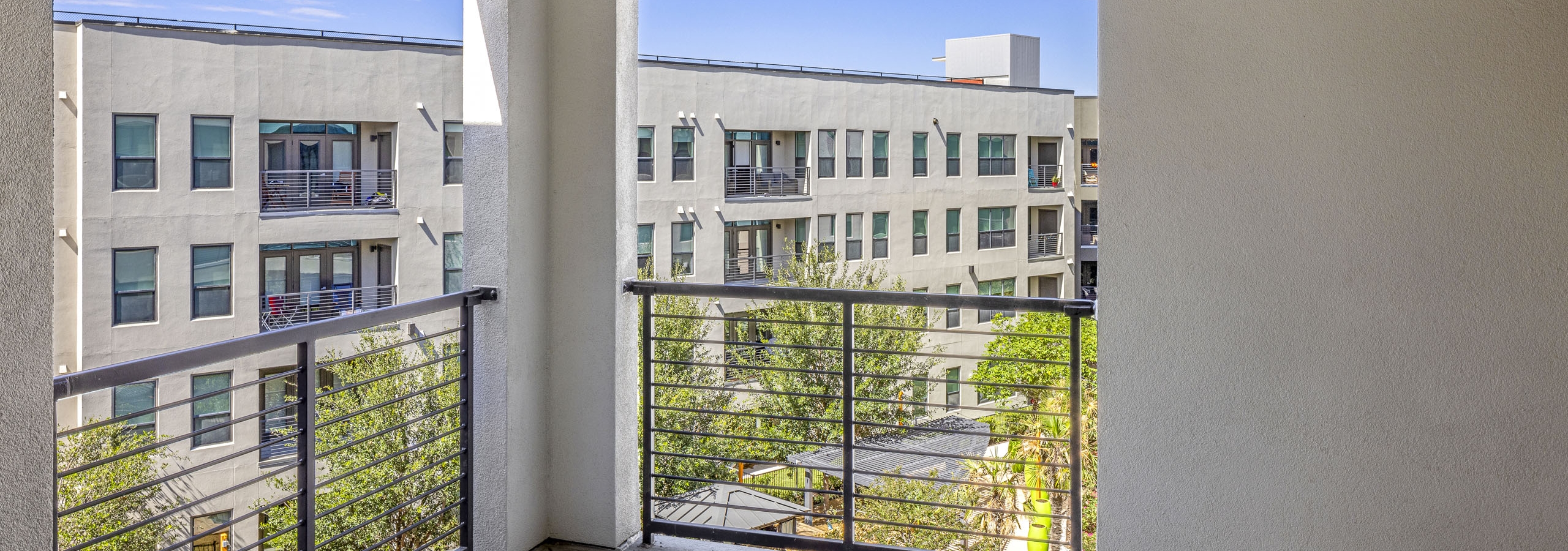 Oversized corner apartment balcony at AMLI on Aldrich with black metal bars and a view of a courtyard and building