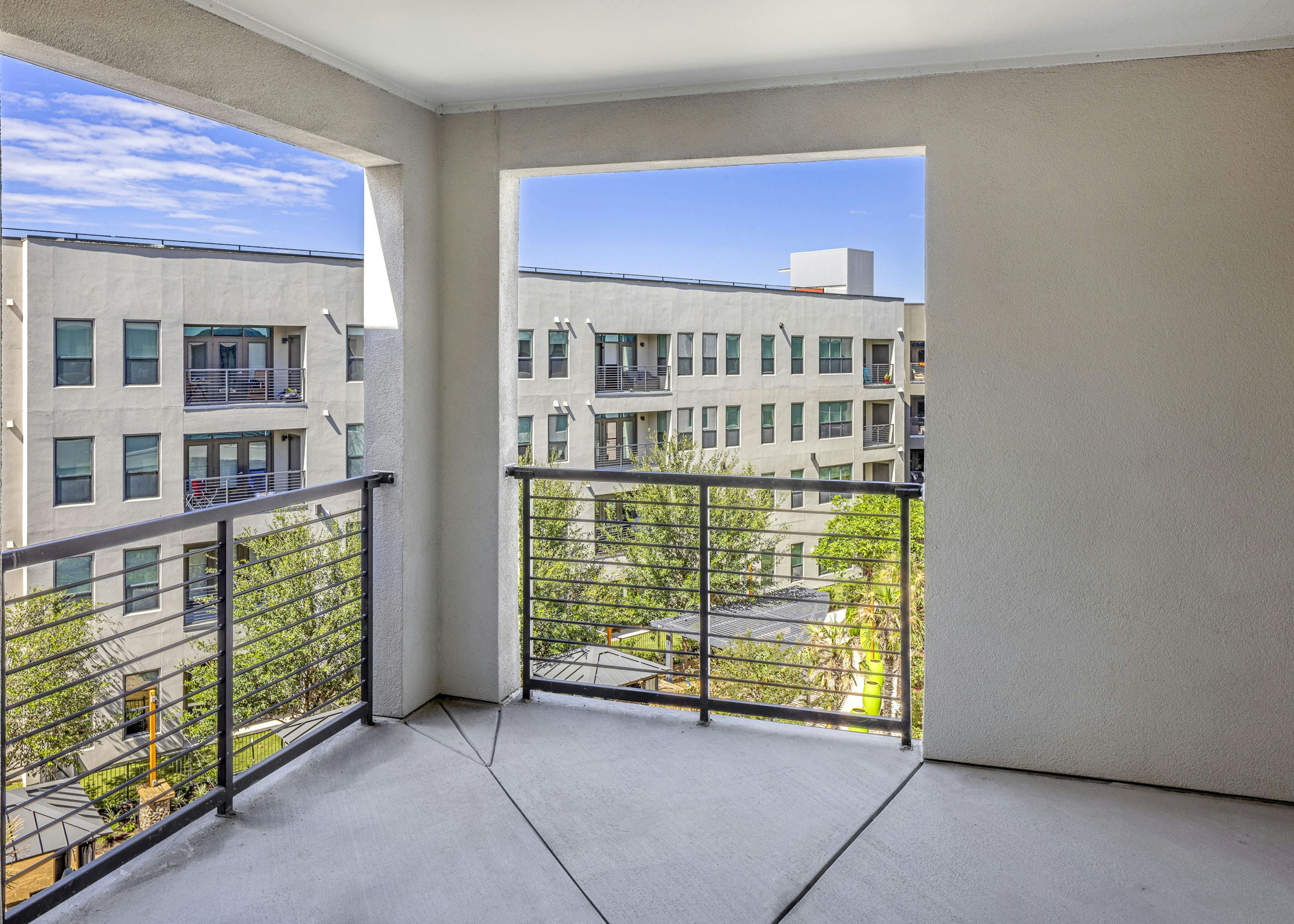 Oversized corner apartment balcony at AMLI on Aldrich with black metal bars and a view of a courtyard and building