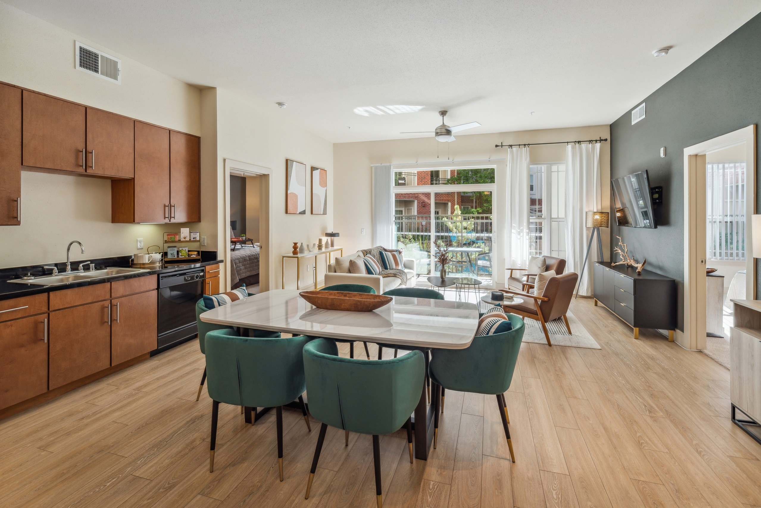 Kitchen and living room at AMLI Park Avenue with  dining table and 6 teal chairs facing living room and view to patio