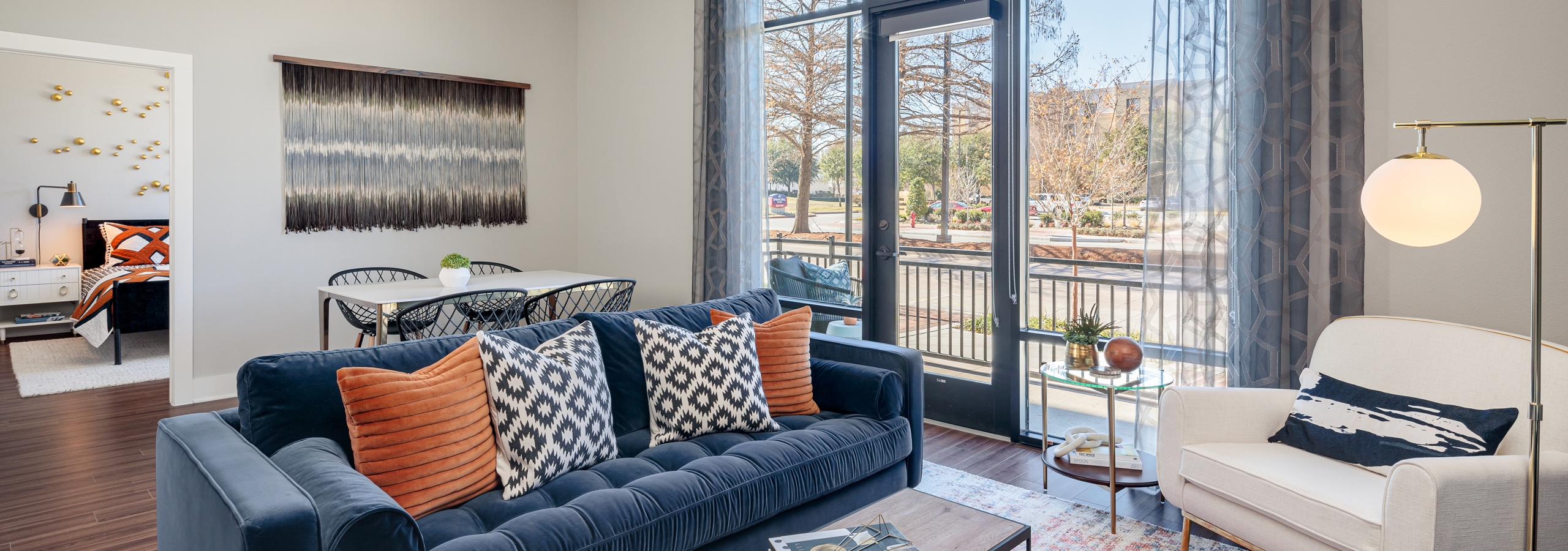 Living room at AMLI Addison with Kember plank flooring and large glass doors leading to balcony with white and blue seating