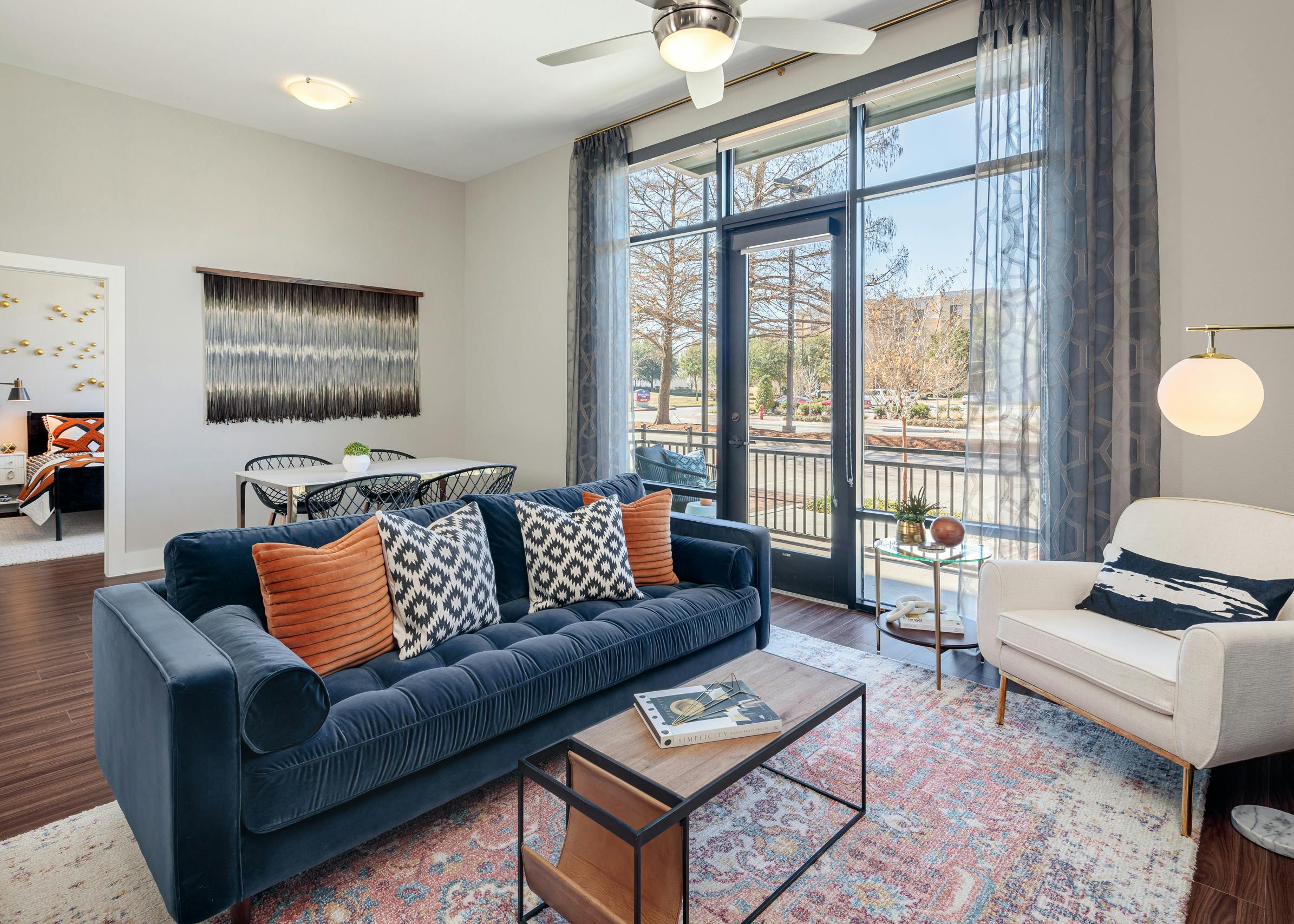Living room at AMLI Addison with Kember plank flooring and large glass doors leading to balcony with white and blue seating