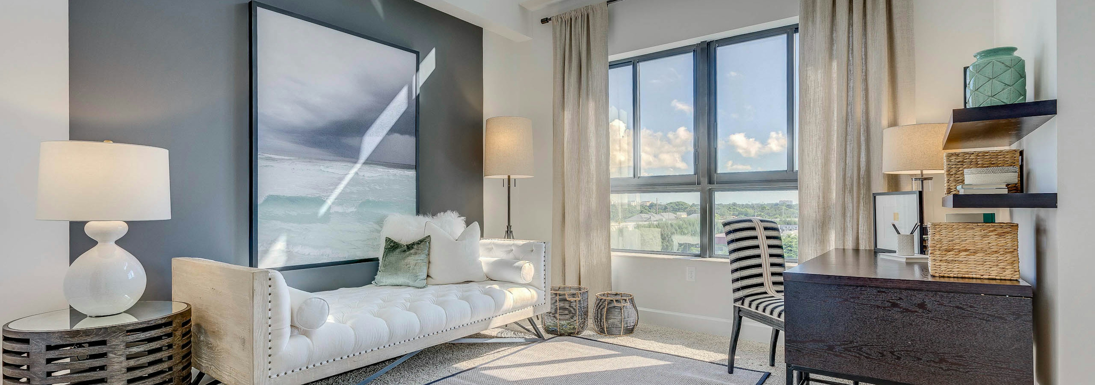 AMLI Joya den with natural light from window, a desk with chair and a white modern chaise lounge underneath a modern painting