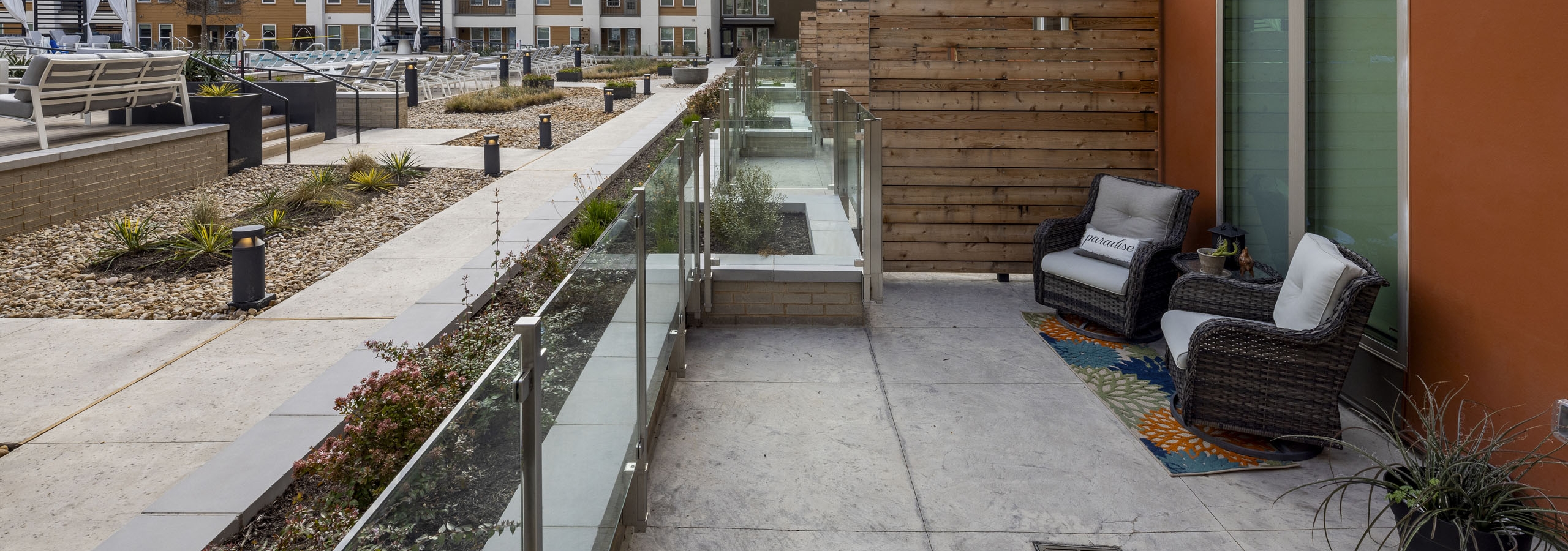 AMLI Branch Park oversized poolside courtyard apartment patio with two lounge chairs and potted landscaping throughout