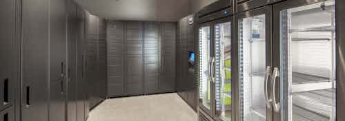 AMLI Downtown Amazon package room with gray metal lockers of varying sizes and two steel refrigerators for perishable packages