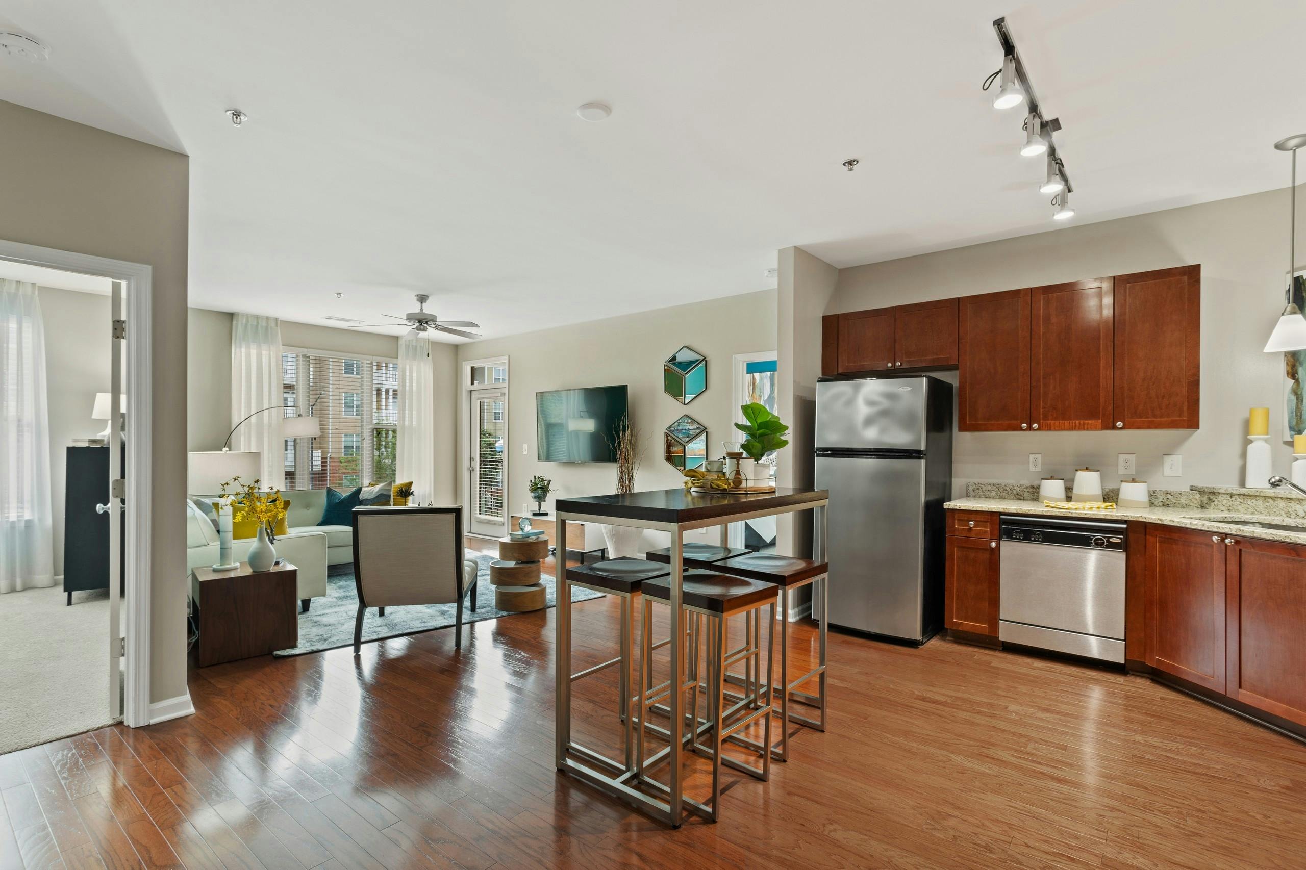 AMLI Lindbergh apartment kitchen and dining table looking into the furnished living room with window and ceiling fan