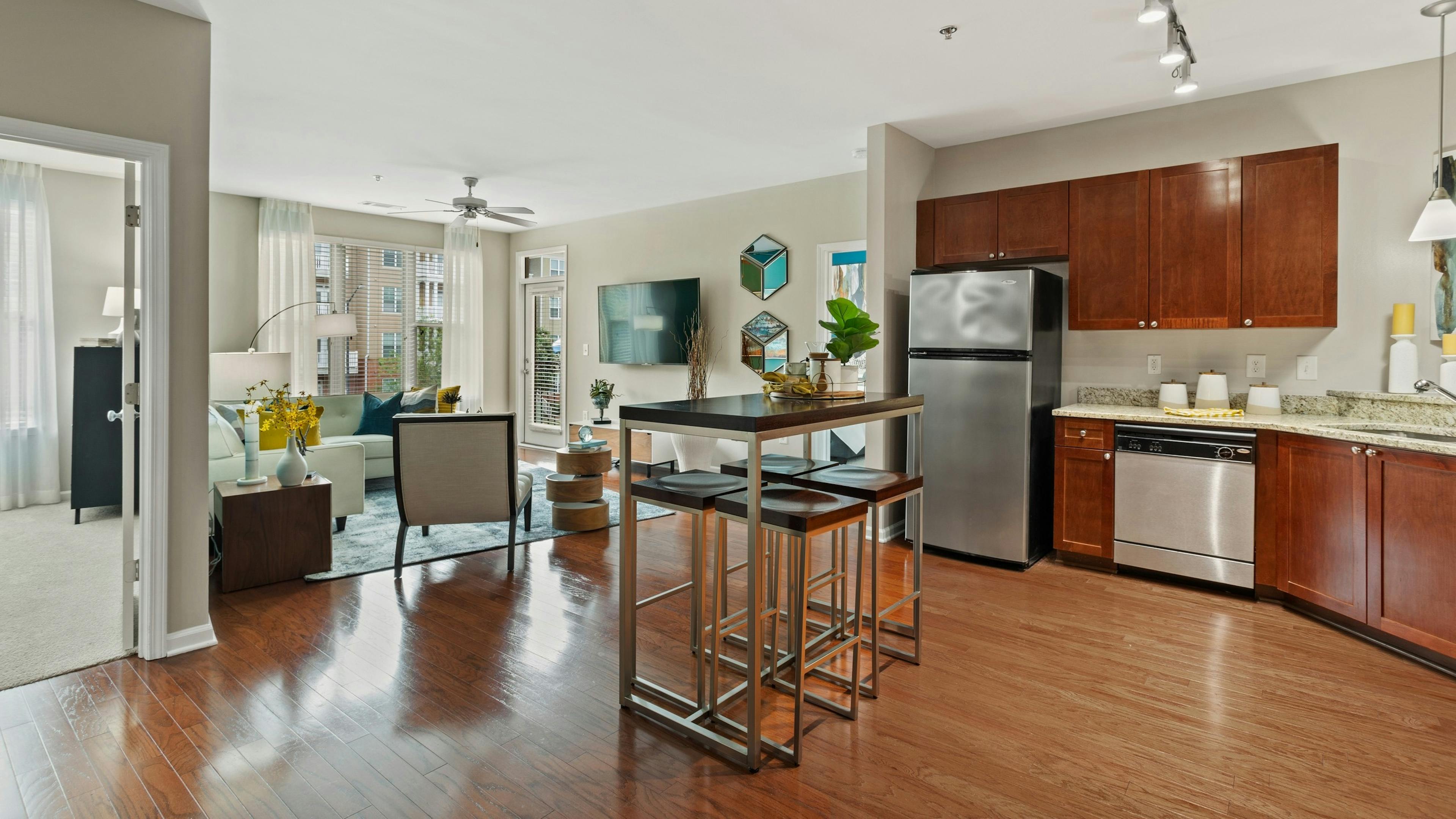 AMLI Lindbergh apartment kitchen and dining table looking into the furnished living room with window and ceiling fan