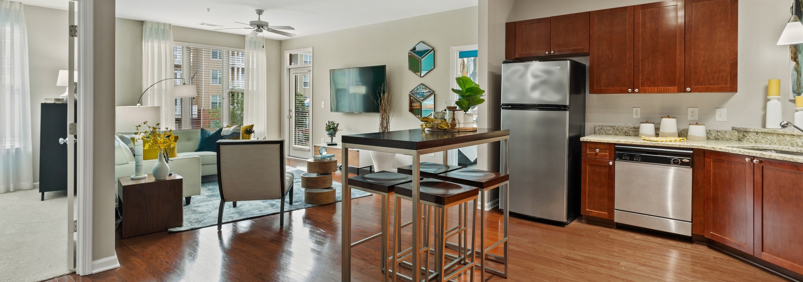 AMLI Lindbergh apartment kitchen and dining table looking into the furnished living room with window and ceiling fan