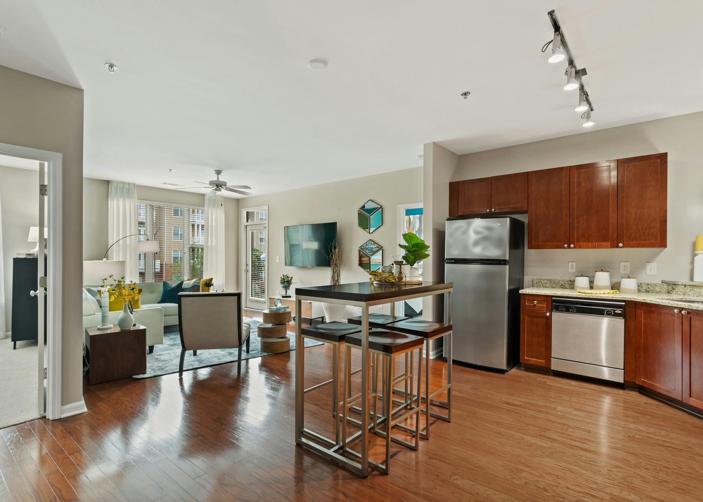 AMLI Lindbergh apartment kitchen and dining table looking into the furnished living room with window and ceiling fan