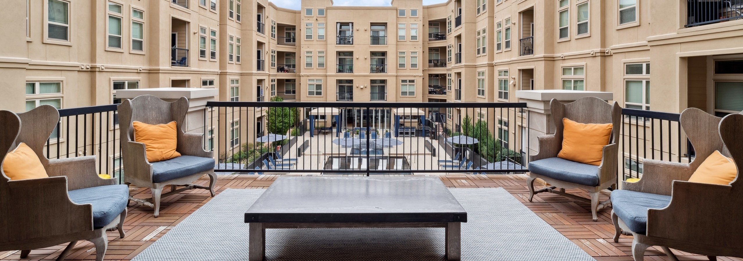 Exterior view of a library outdoor lounge at AMLI RidgeGate with chairs and area rug and table and a view of the pool area