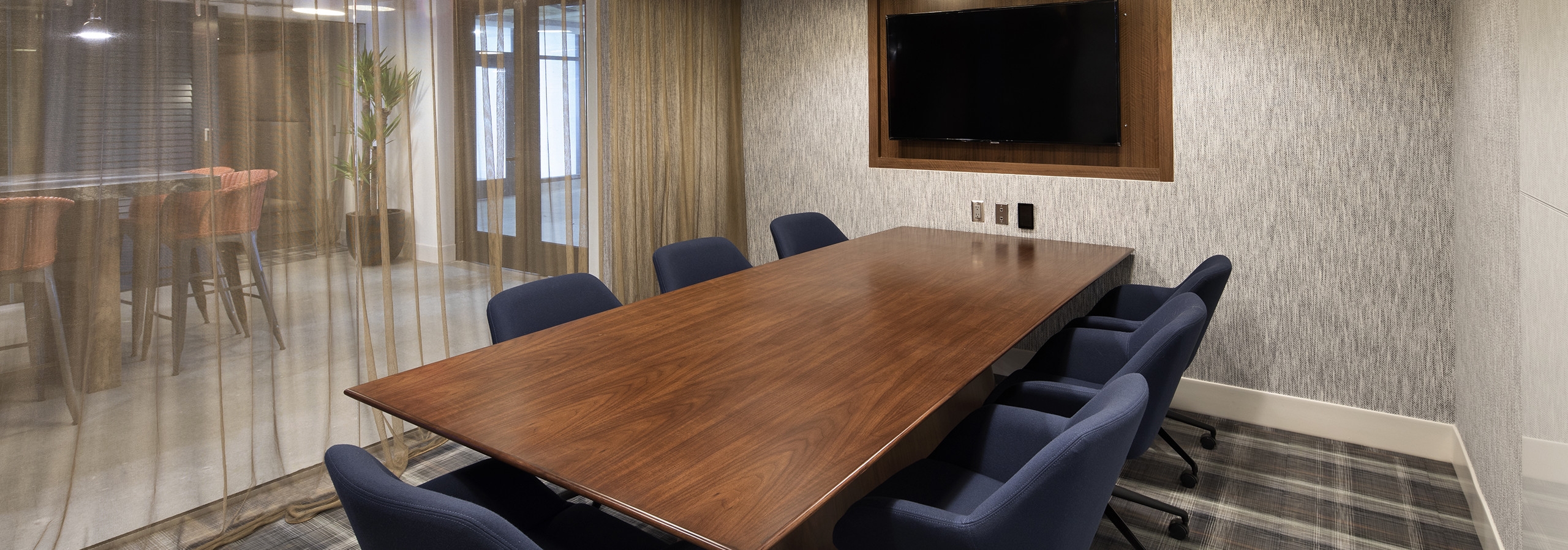 Interior of conference room with large table and chairs, big screen TV and sheer curtains at AMLI Marina Del Rey apartments