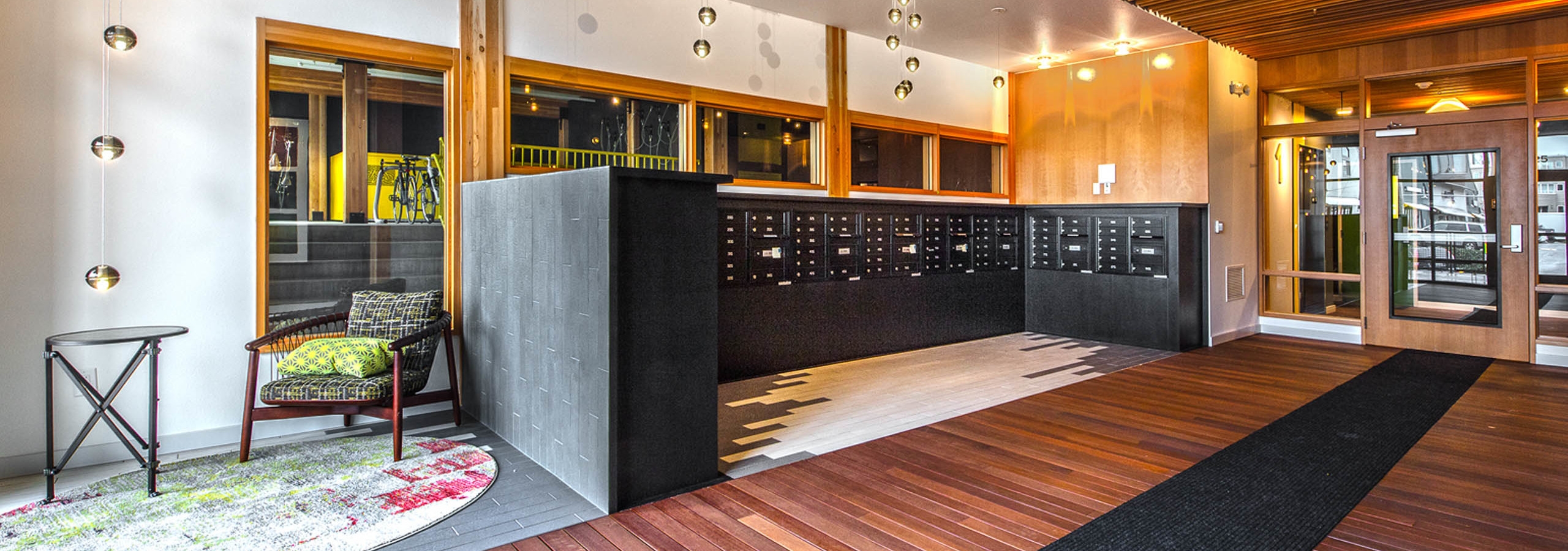 One of two resident mailbox areas at AMLI Wallingford with wooden floors and dark mailboxes and seating area