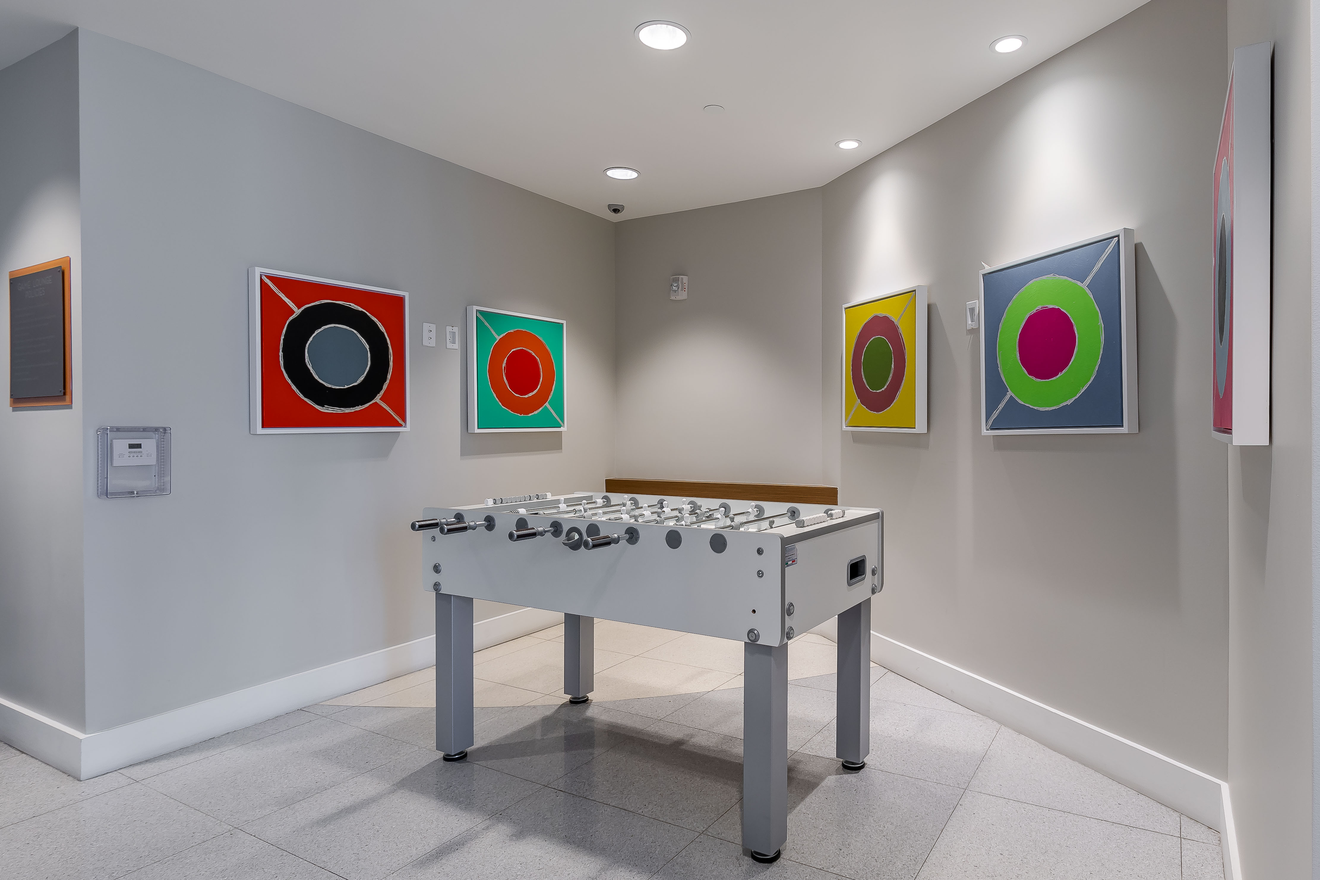 Interior view of the game room at AMLI 8800 apartments with a foosball table and colorful framed circle artwork on the wall 