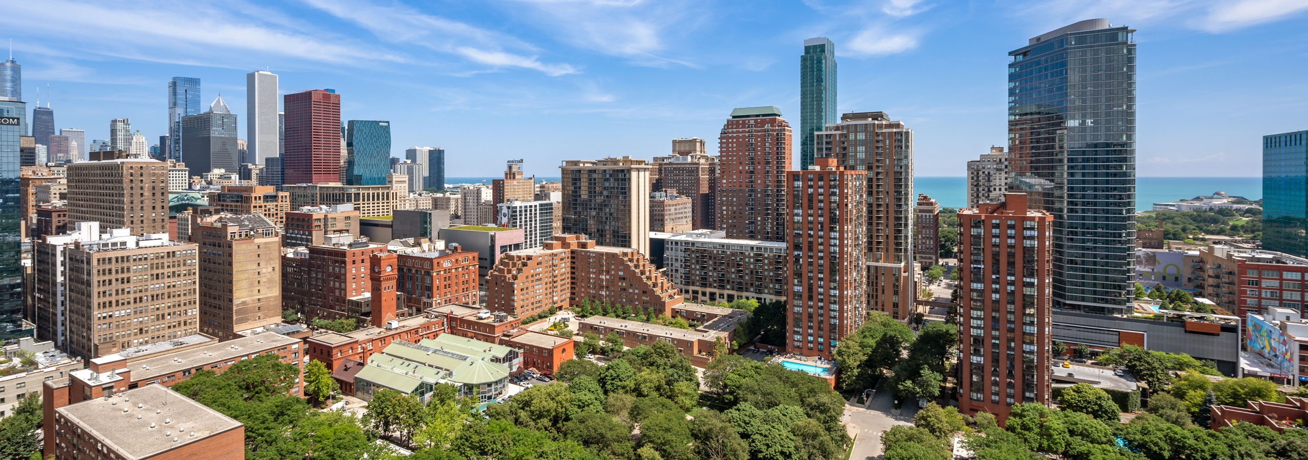 View of the city from AMLI 900 rooftop with city buildings and green trees and blue sky with wispy clouds