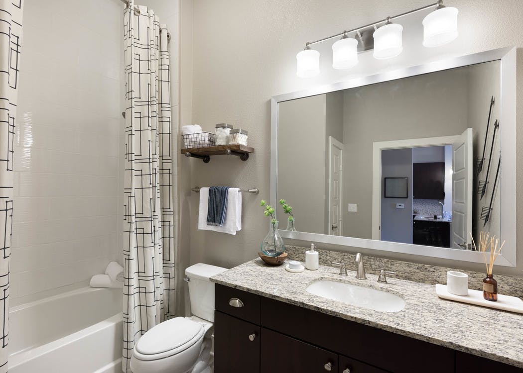 AMLI Frisco Crossing bathroom with and espresso cabinetry with granite countertop and framed mirror above and oval garden tub