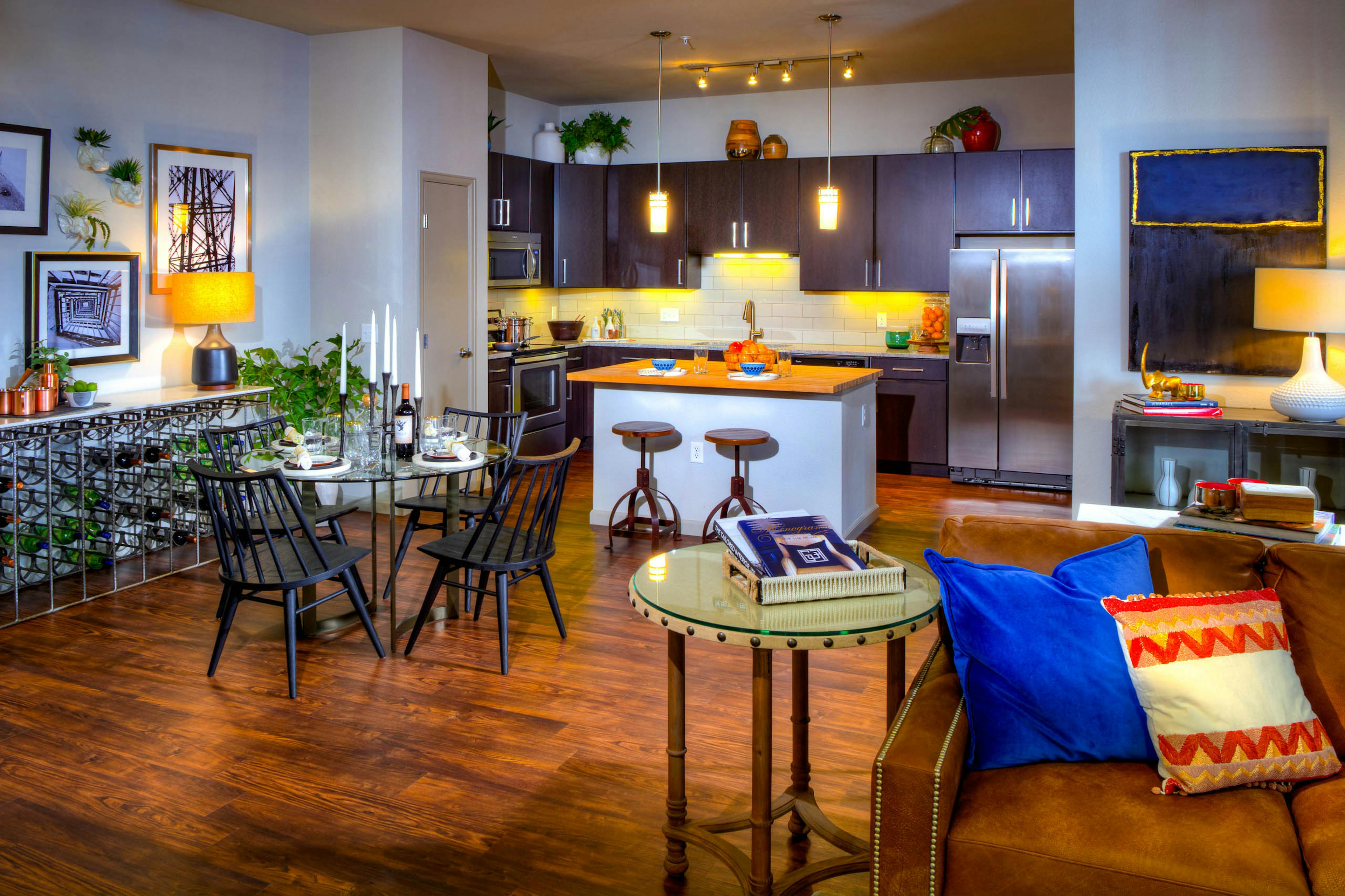 Interior view of a living room and kitchen at AMLI Denargo Market apartments with a dining room table and chairs and lamps