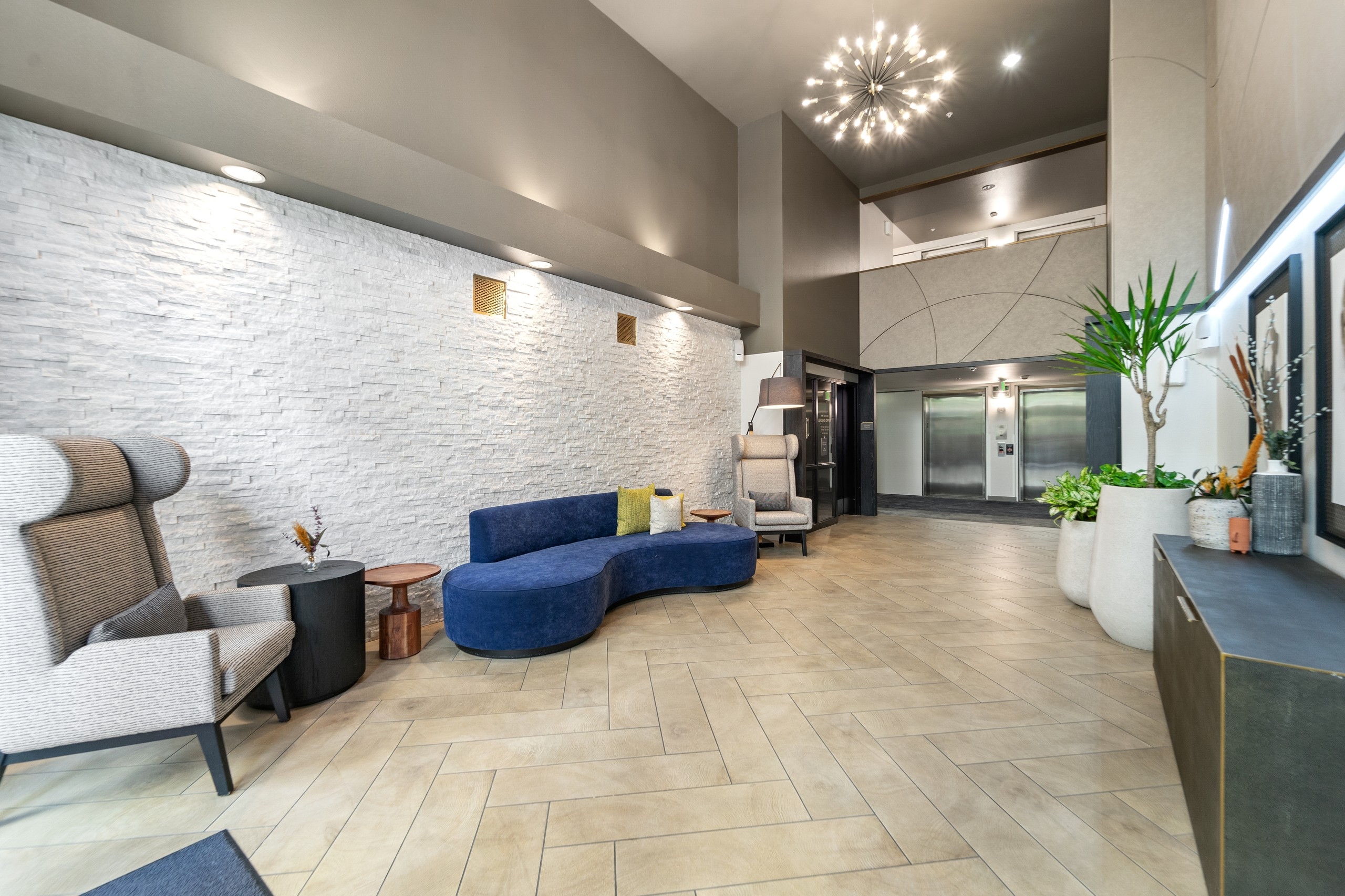 Interior view of lobby at AMLI Bellevue Park apartments with blue couch and 2 chairs and view of 2 elevators