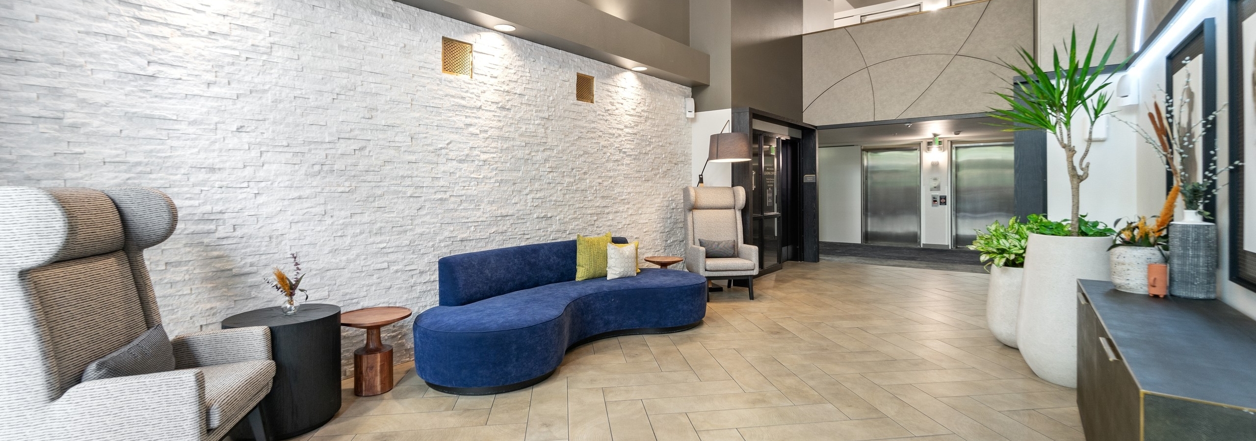Interior view of lobby at AMLI Bellevue Park apartments with blue couch and 2 chairs and view of 2 elevators