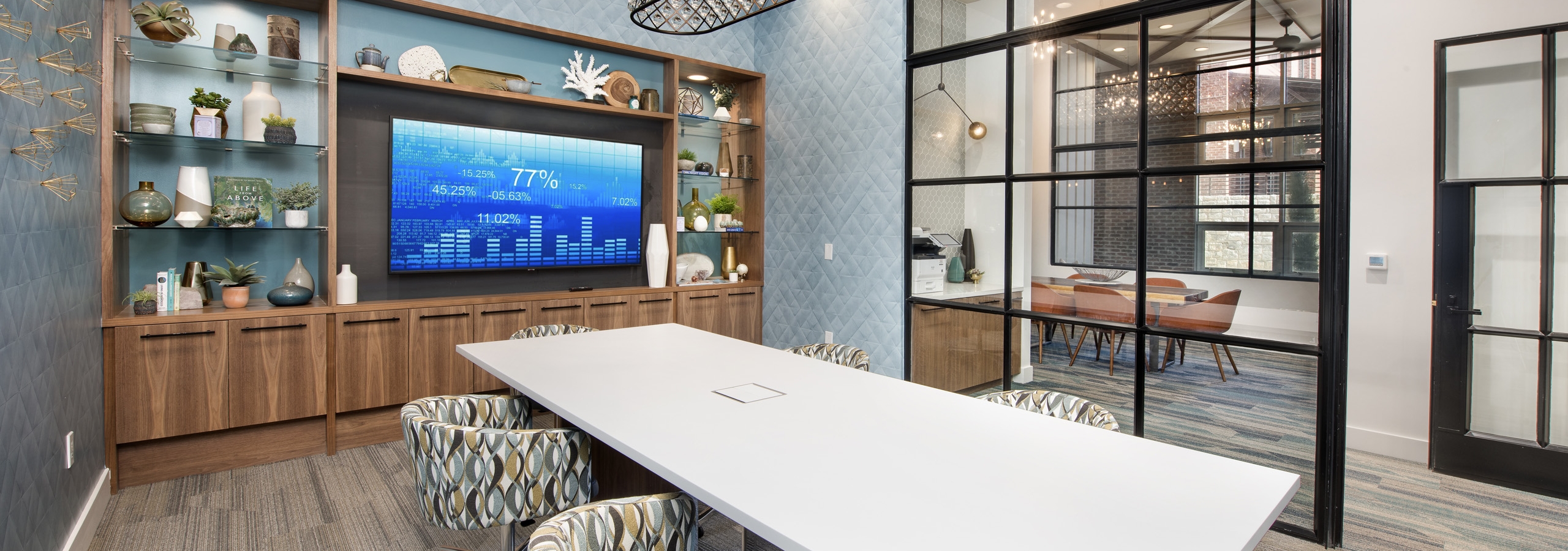 Interior of tech center conference room at AMLI Decatur with large screen TV and a long white table and six patterned chairs