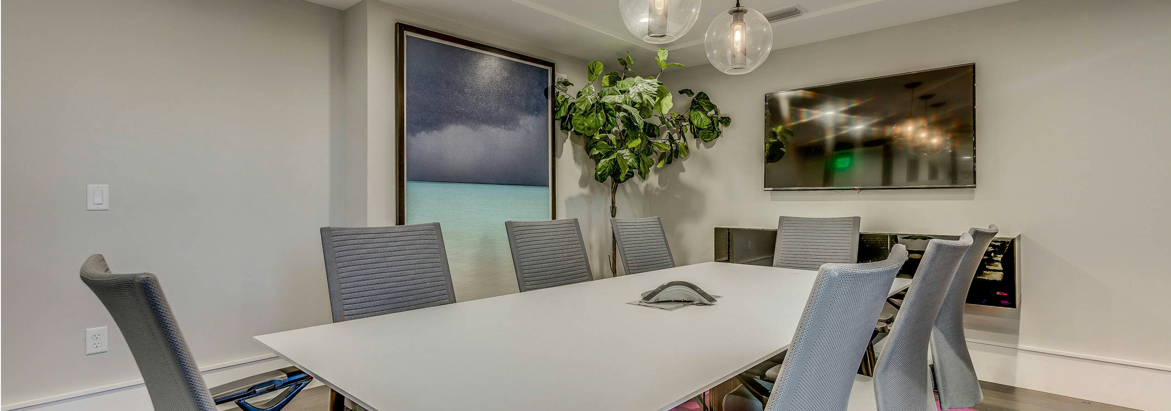 Interior conference room space at AMLI Joya with rectangular conference table and chairs, mounted tv and modern decor